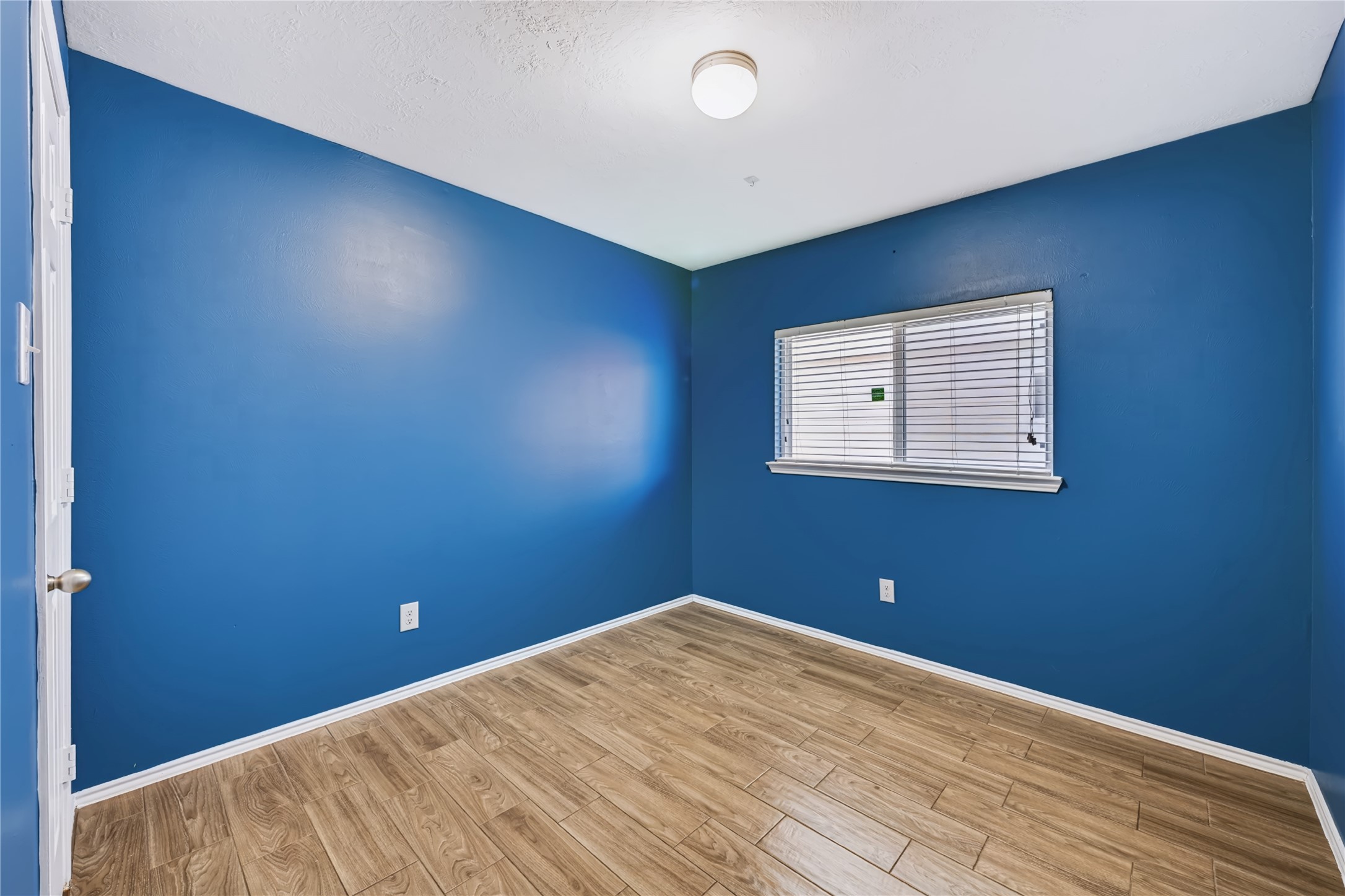Bright and inviting secondary bedroom featuring rich wood-look tile flooring, a large window with natural light, and a flexible layout. Bright and inviting secondary bedroom featuring rich wood-look tile flooring, a large window with natural light, and a flexible layout.