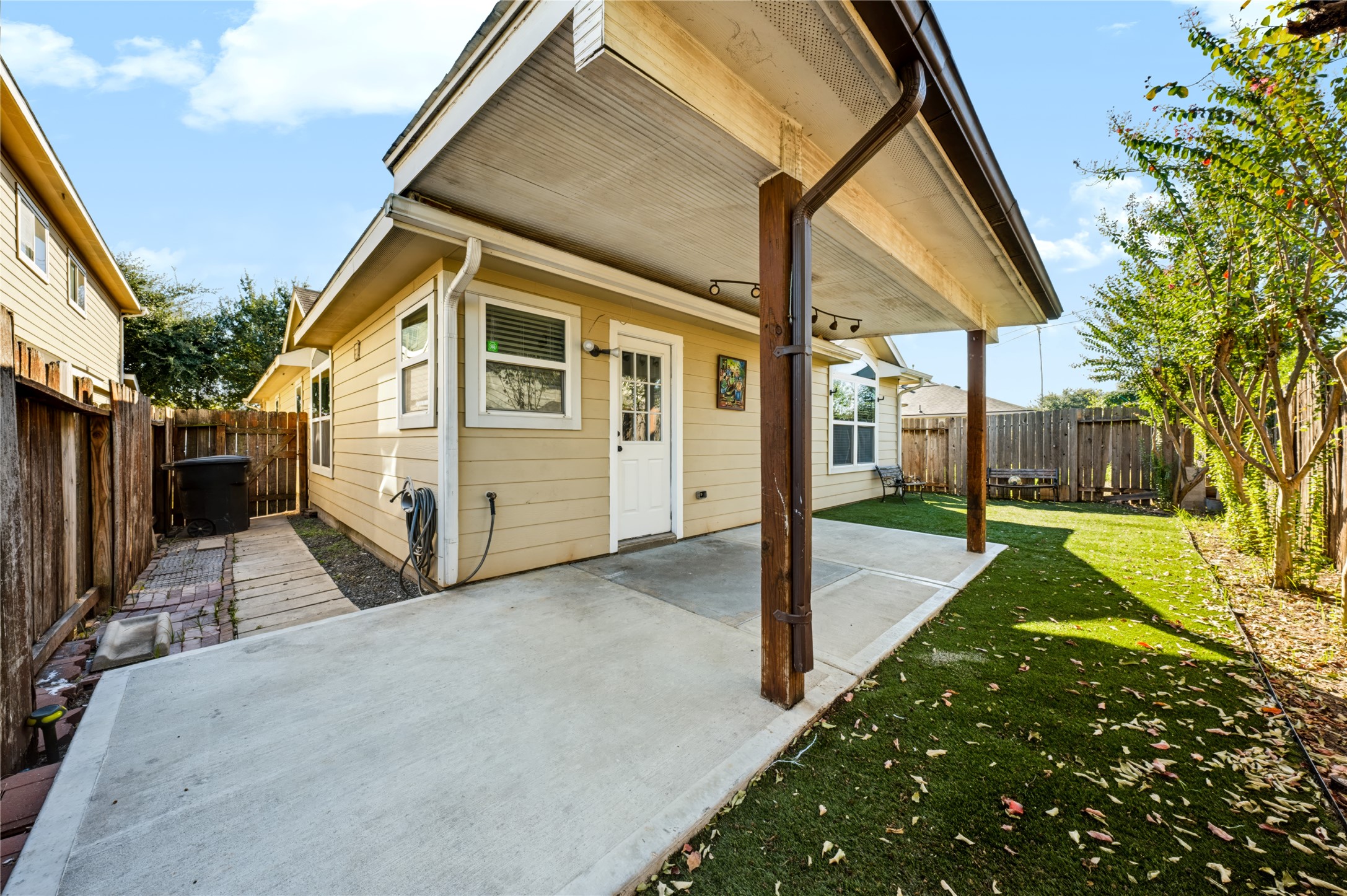 Private backyard featuring a covered back patio, a concrete slab area, and a neatly maintained yardideal for outdoor relaxing or entertaining