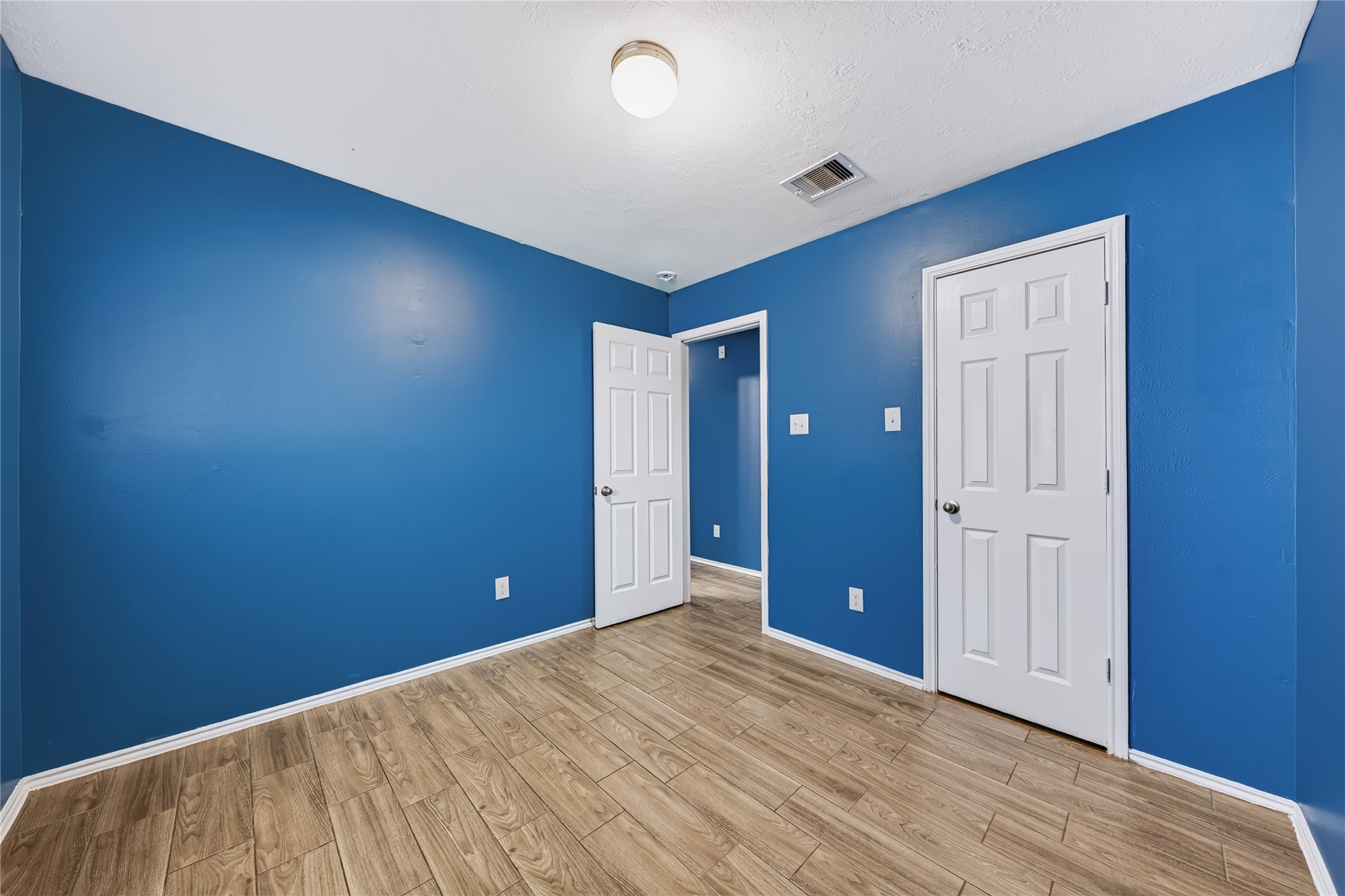 Bright and inviting secondary bedroom featuring rich wood-look tile flooring, a large window with natural light, and a flexible layout. Bright and inviting secondary bedroom featuring rich wood-look tile flooring, a large window with natural light, and a flexible layout.