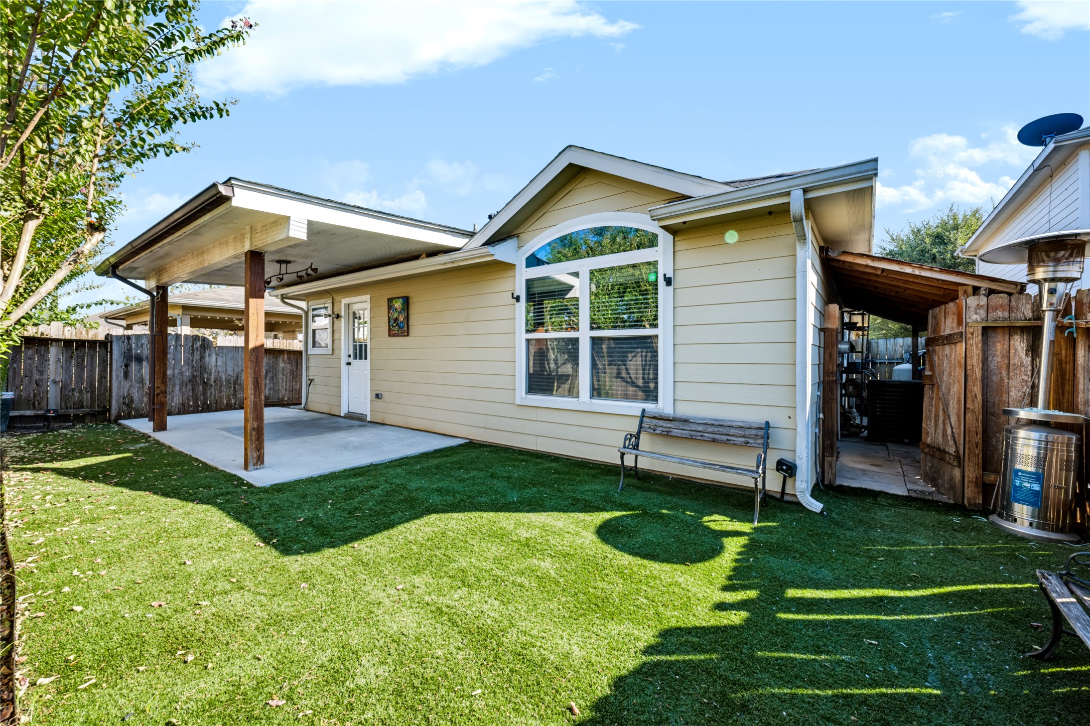 Private backyard featuring a covered back patio, a concrete slab area, and a neatly maintained yardideal for outdoor relaxing or entertaining