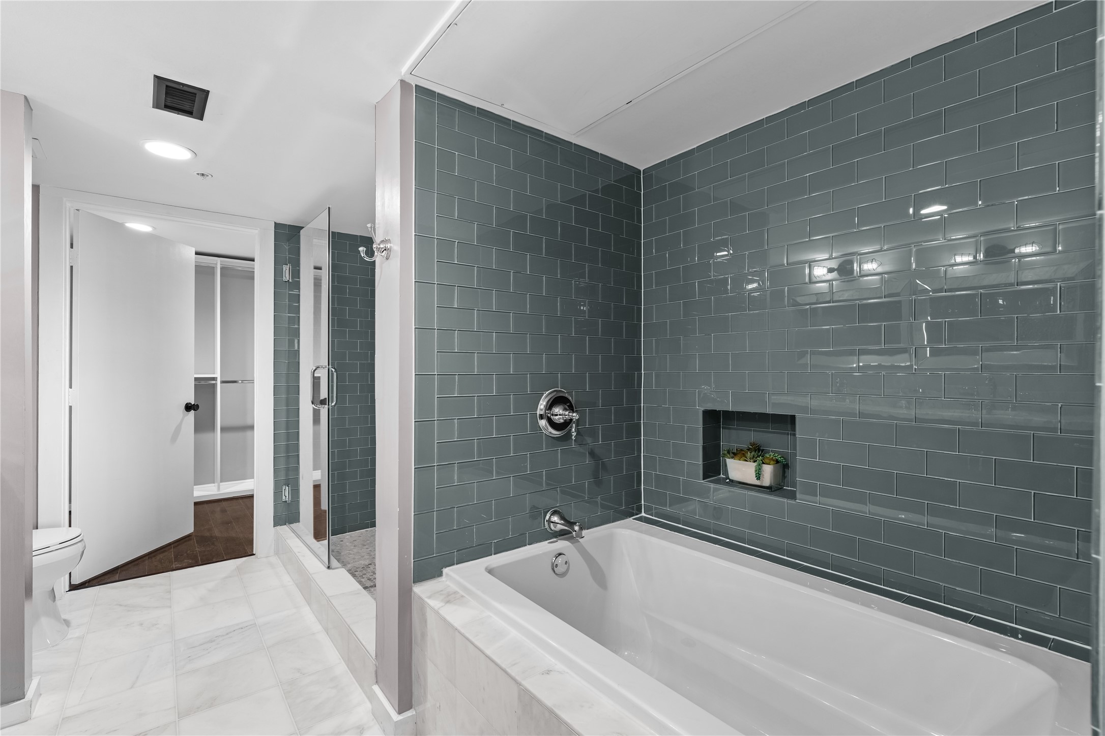 A closer look at the remodeled primary bath highlights the separate soaking tub, oversized glass enclosed shower and striking tilework that adds depth and contrast to the space.