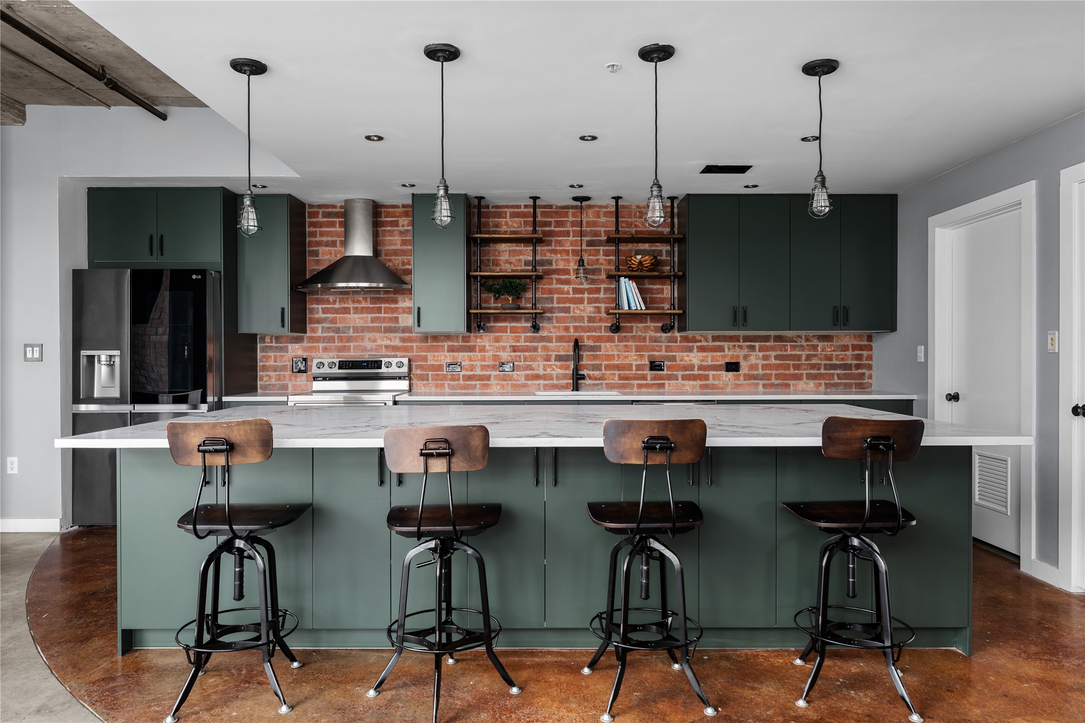 A full view of the completely renovated kitchen highlights the expansive island, custom cabinetry and exposed brick, blending modern refinement with the lofts original industrial character.