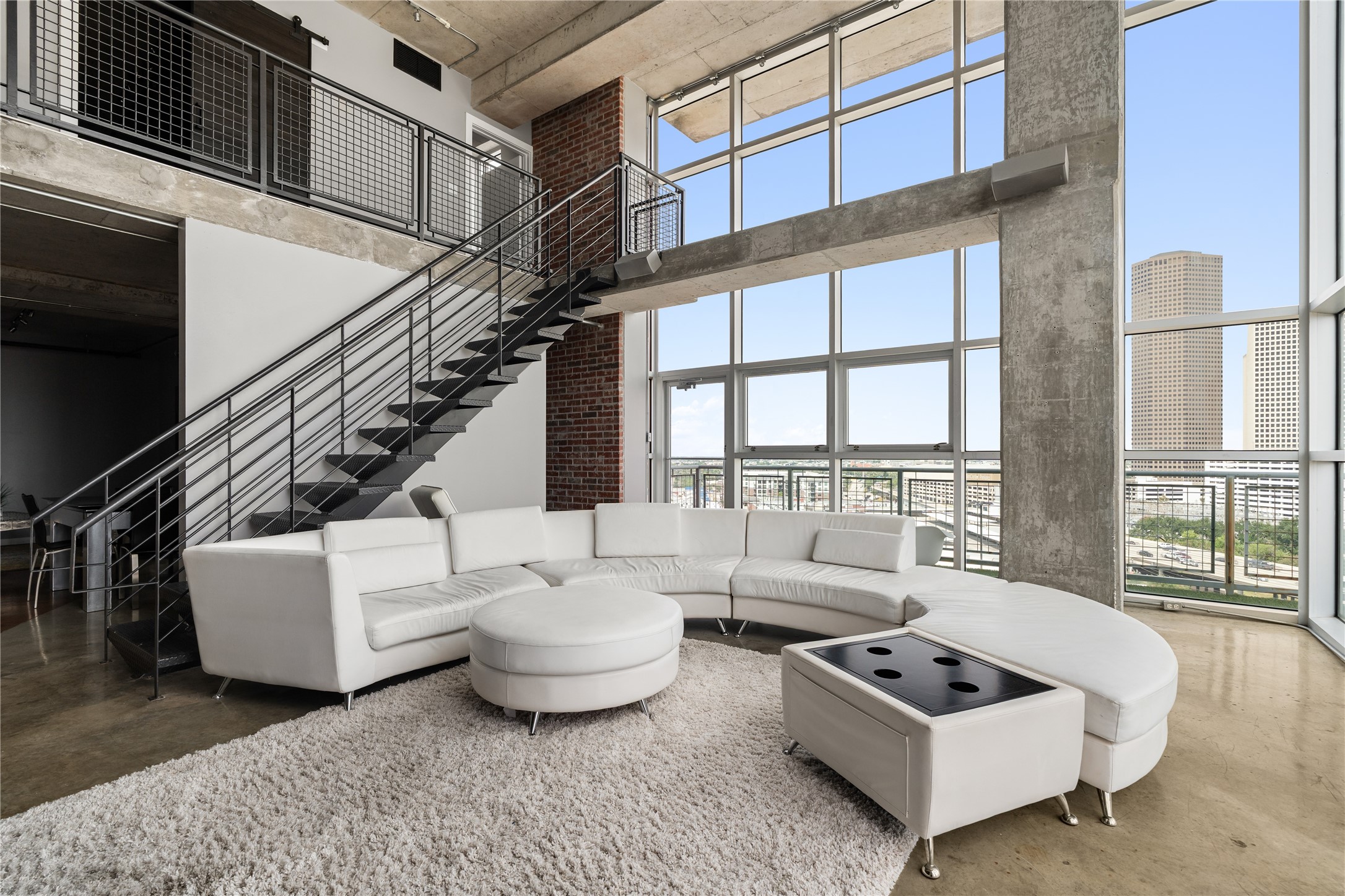 A wider perspective captures the impressive volume of the two story living room, where soaring windows, exposed concrete and the open staircase create a true loft experience.