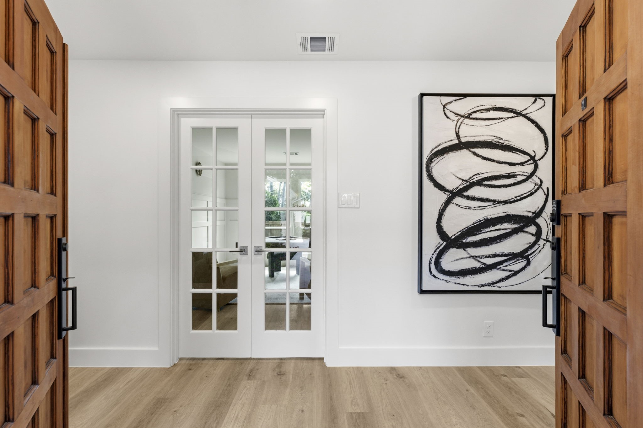 The welcoming foyer offers a beautiful first impression with warm wood flooring, designer lighting, and thoughtfully curated finishes.