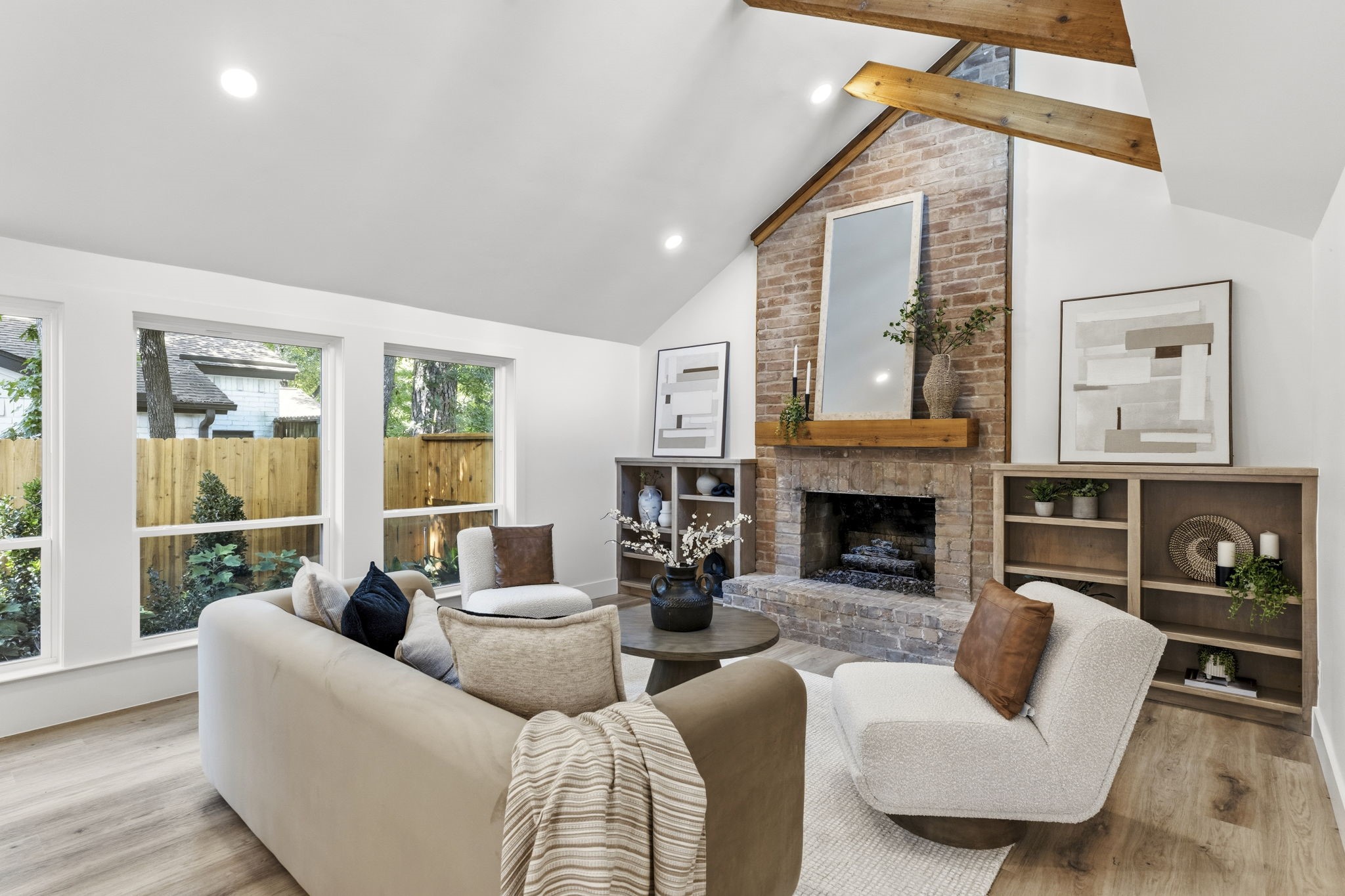 The dramatic floor-to-ceiling brick fireplace anchors the living room, creating a striking architectural centerpiece beneath the soaring vaulted ceiling.