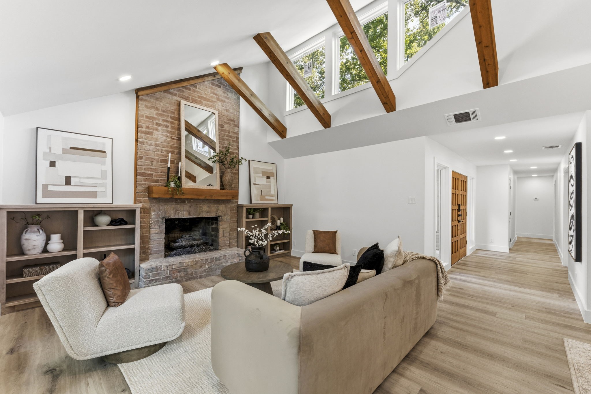 Open-concept living and dining space highlighted by soaring vaulted ceilings with exposed wood beams and abundant natural light.