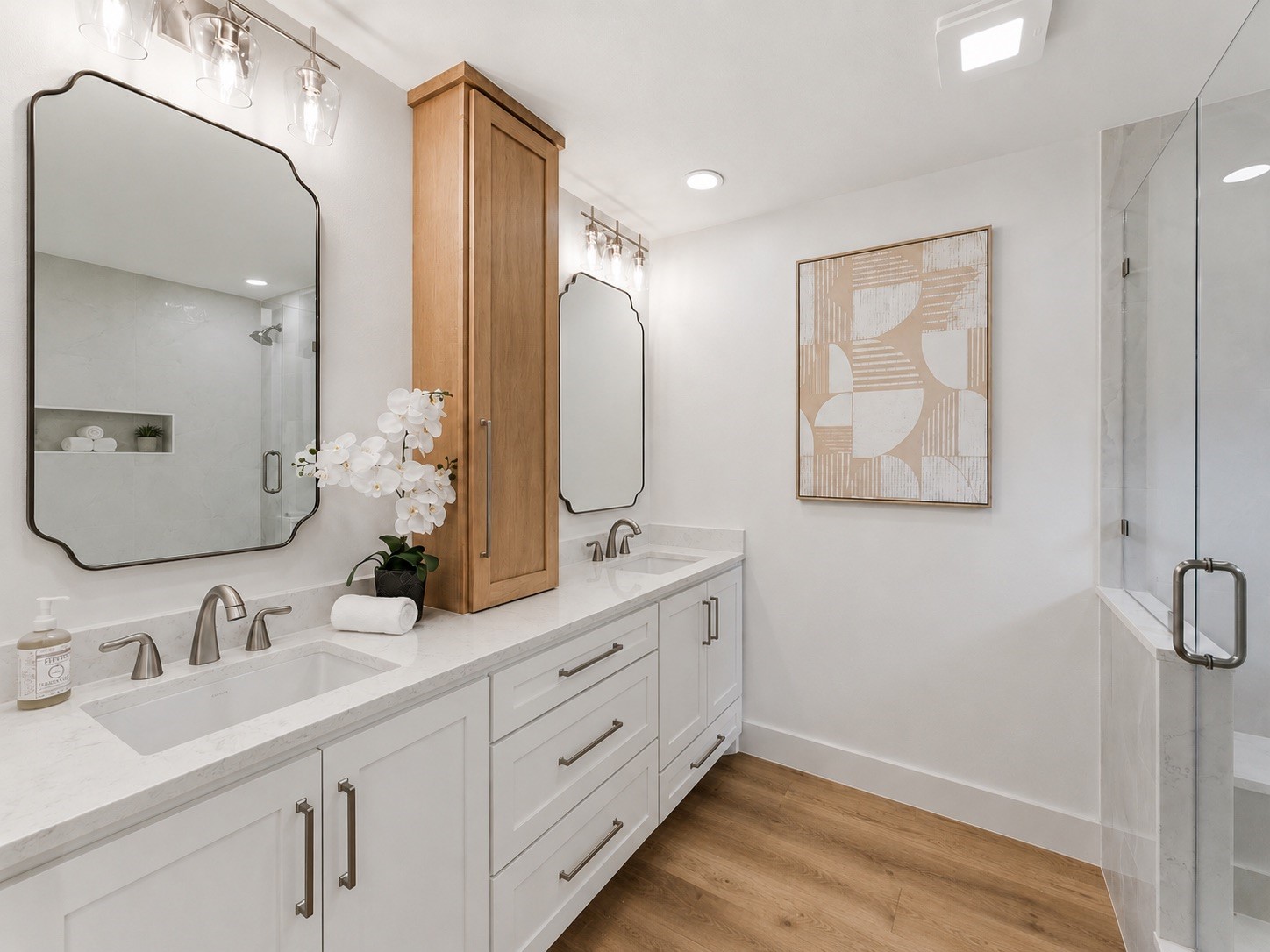 The spa-inspired primary bath with dual quartz vanities, custom cabinetry, designer mirrors, and elegant lighting.