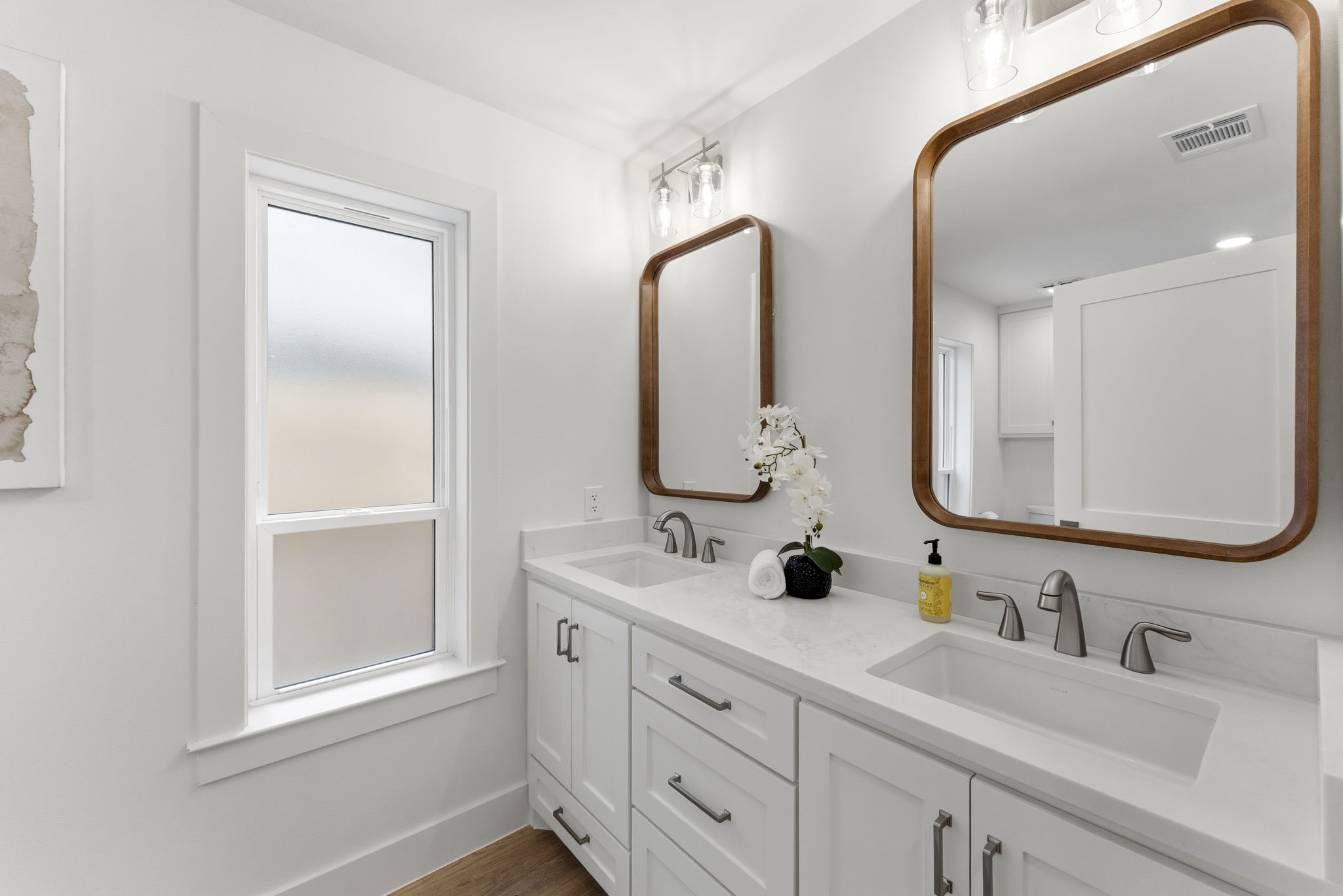 This beautifully updated secondary bath features a quartz vanity with custom cabinetry, designer lighting, modern fixtures, and timeless tile finishes.