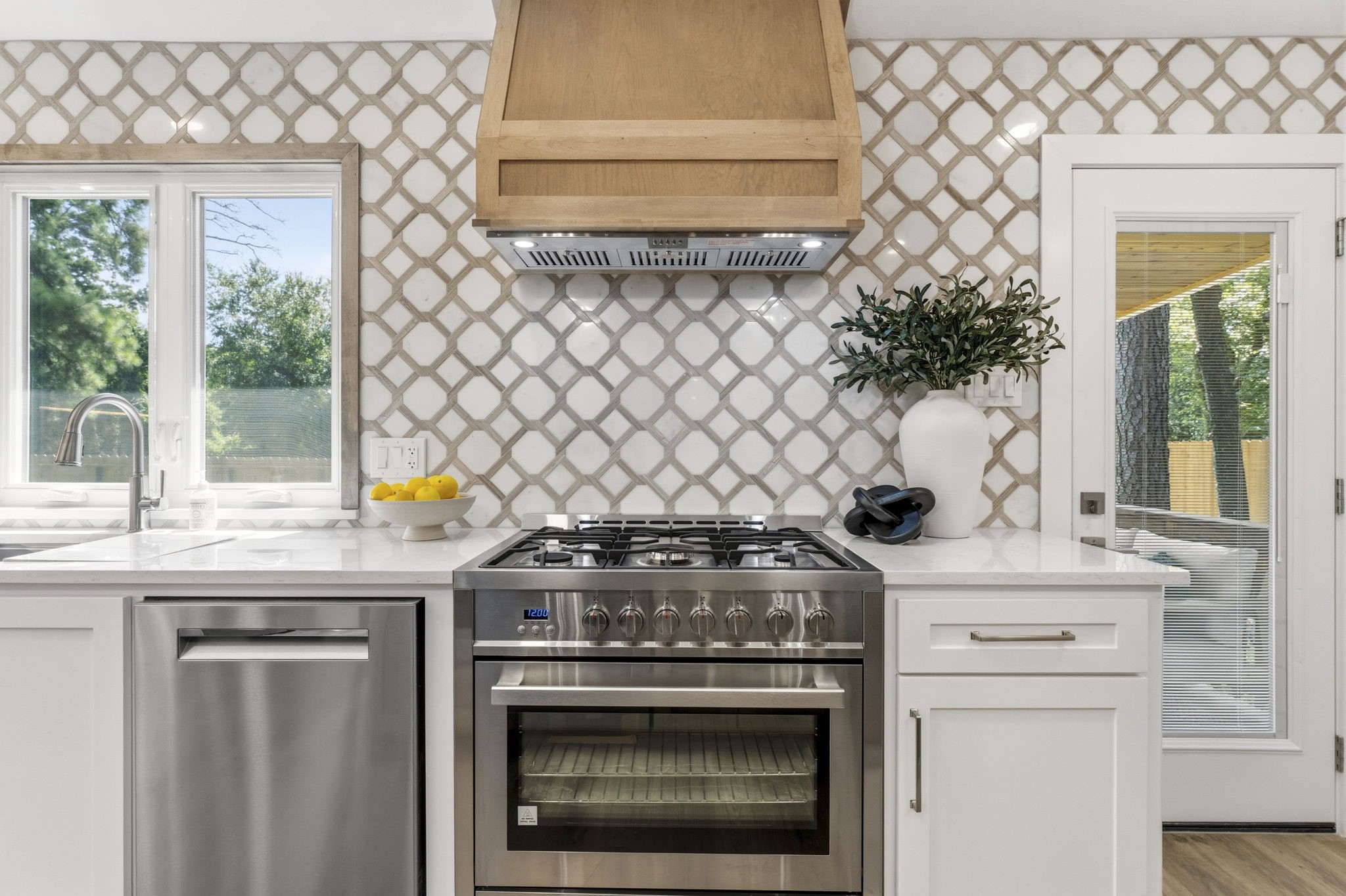 Designed with the home chef in mind, this stunning kitchen showcases a premium suite of high-end stainless steel appliances, including a professional-style range beneath a custom wood vent hood.