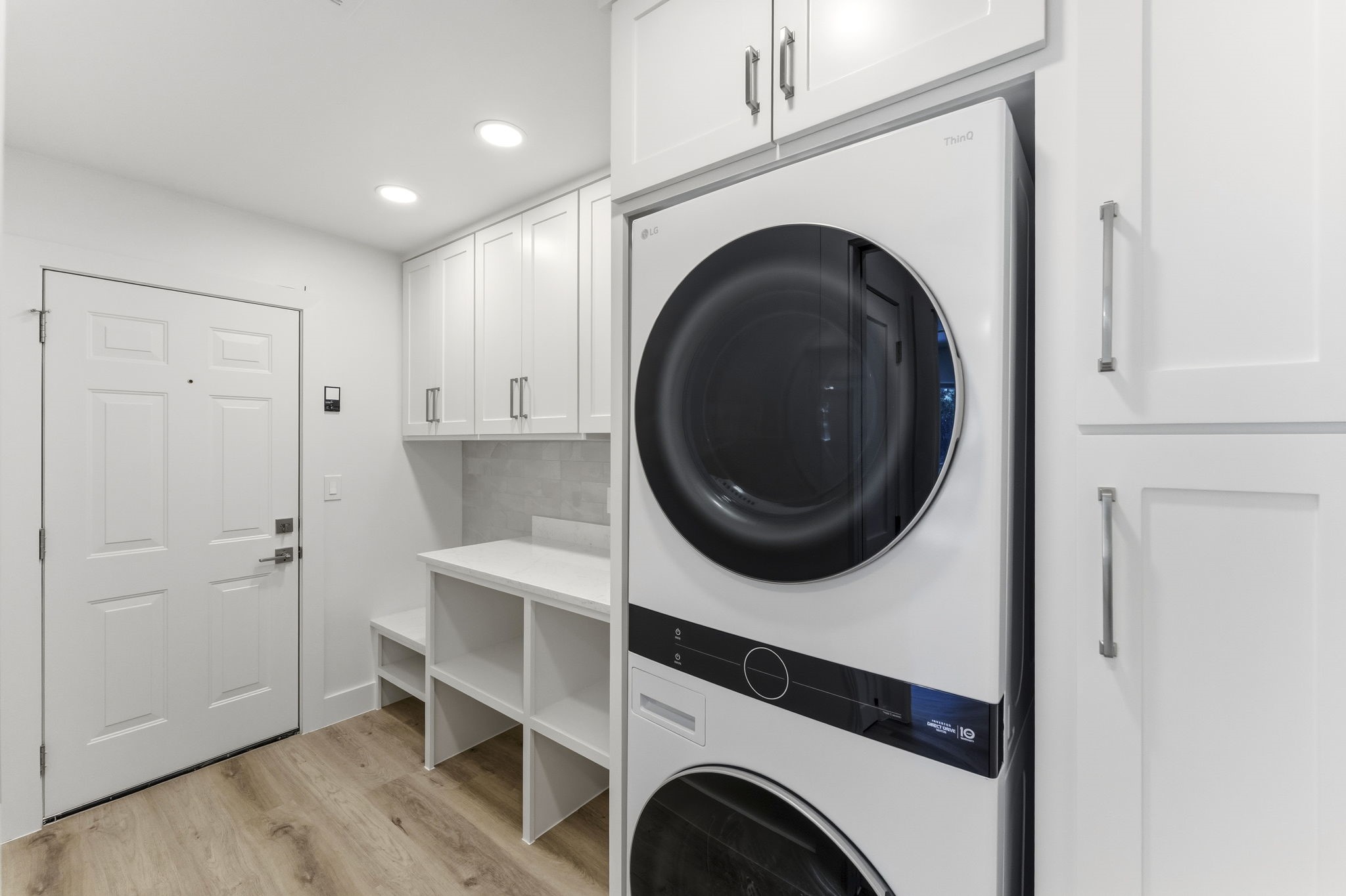 Amazing laundry room with included stackable washer and dryer, custom built-ins, open shelving, and folding space.
