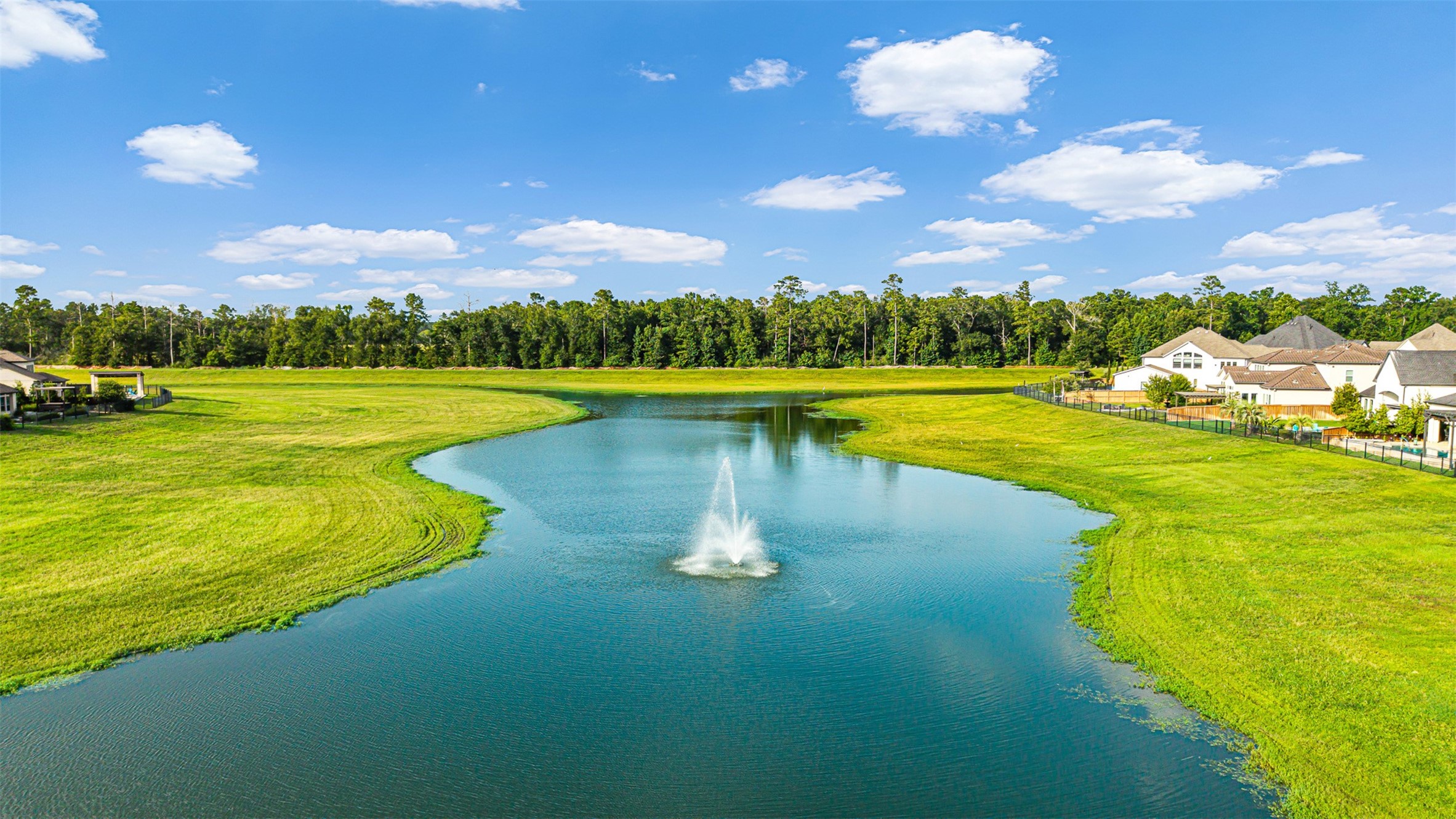 Scenic catch-and-release pond with a central fountain features winding shorelines framed by manicured green space and neighborhood homes.
