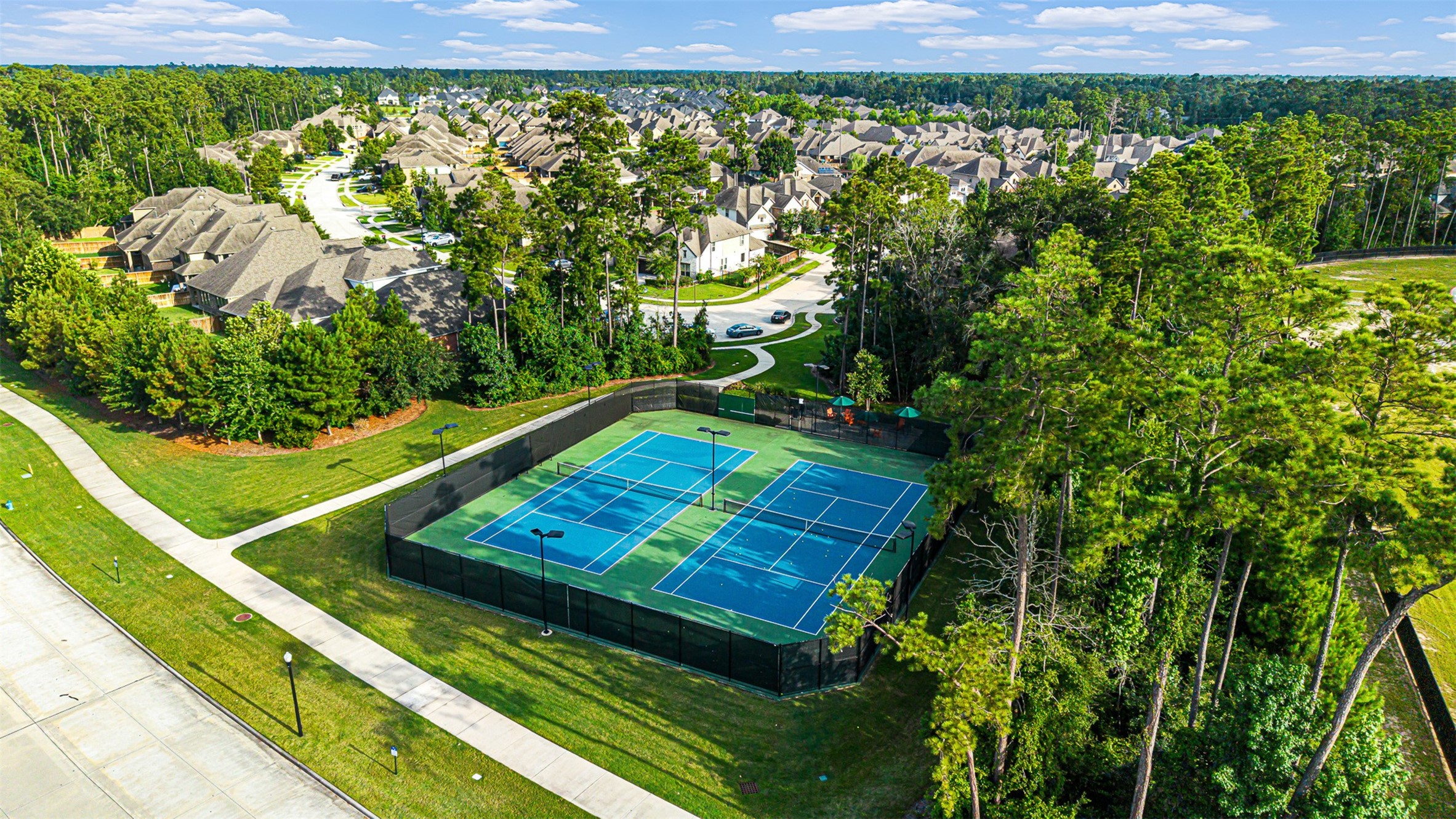 Enjoy friendly matches on the vibrant community tennis courts, beautifully enclosed by protective fencing and tall pine trees.