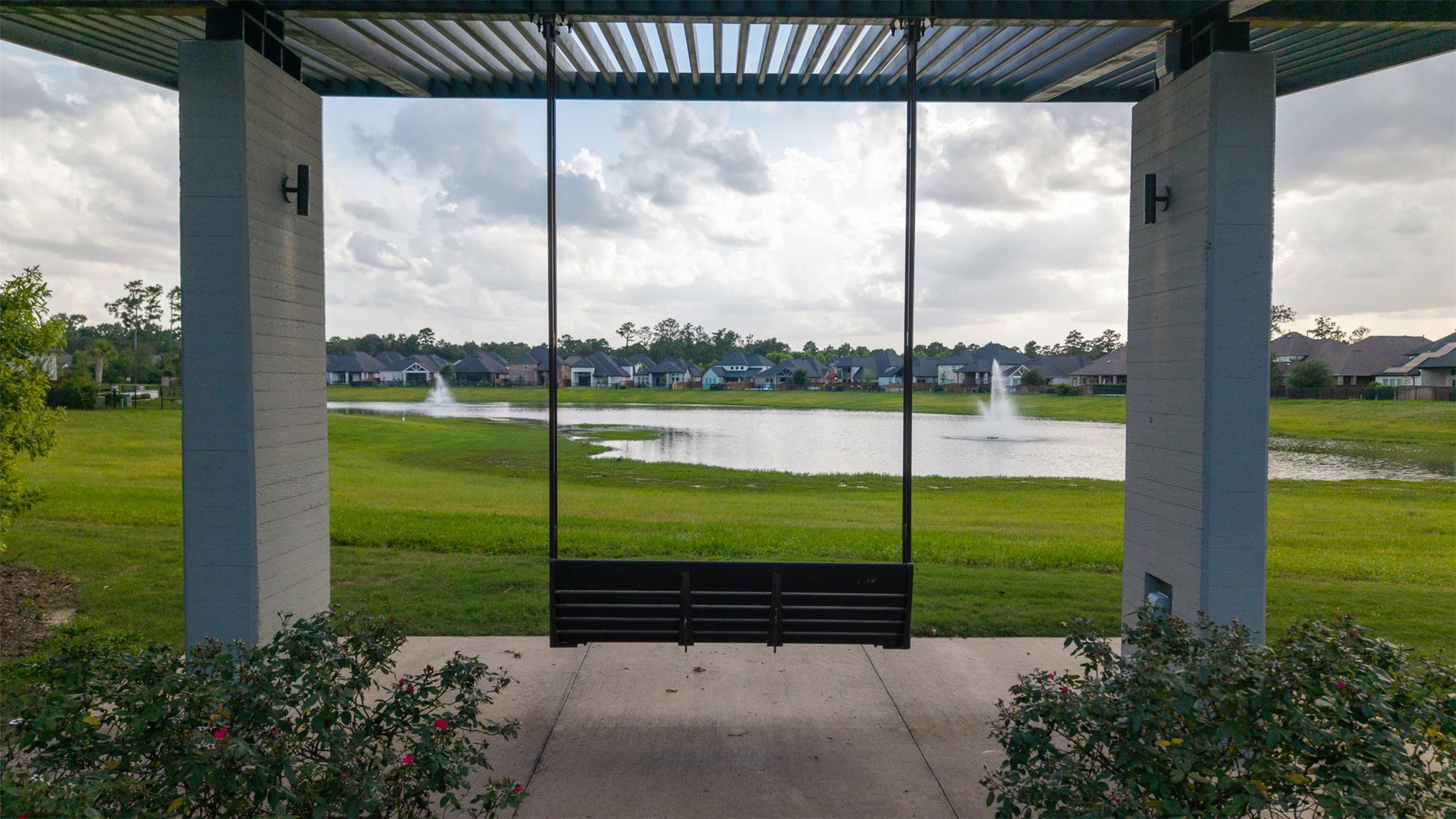 A covered pavilion swing frames tranquil views of the community catch-and-release pond, complete with central water fountains and expansive green spaces.