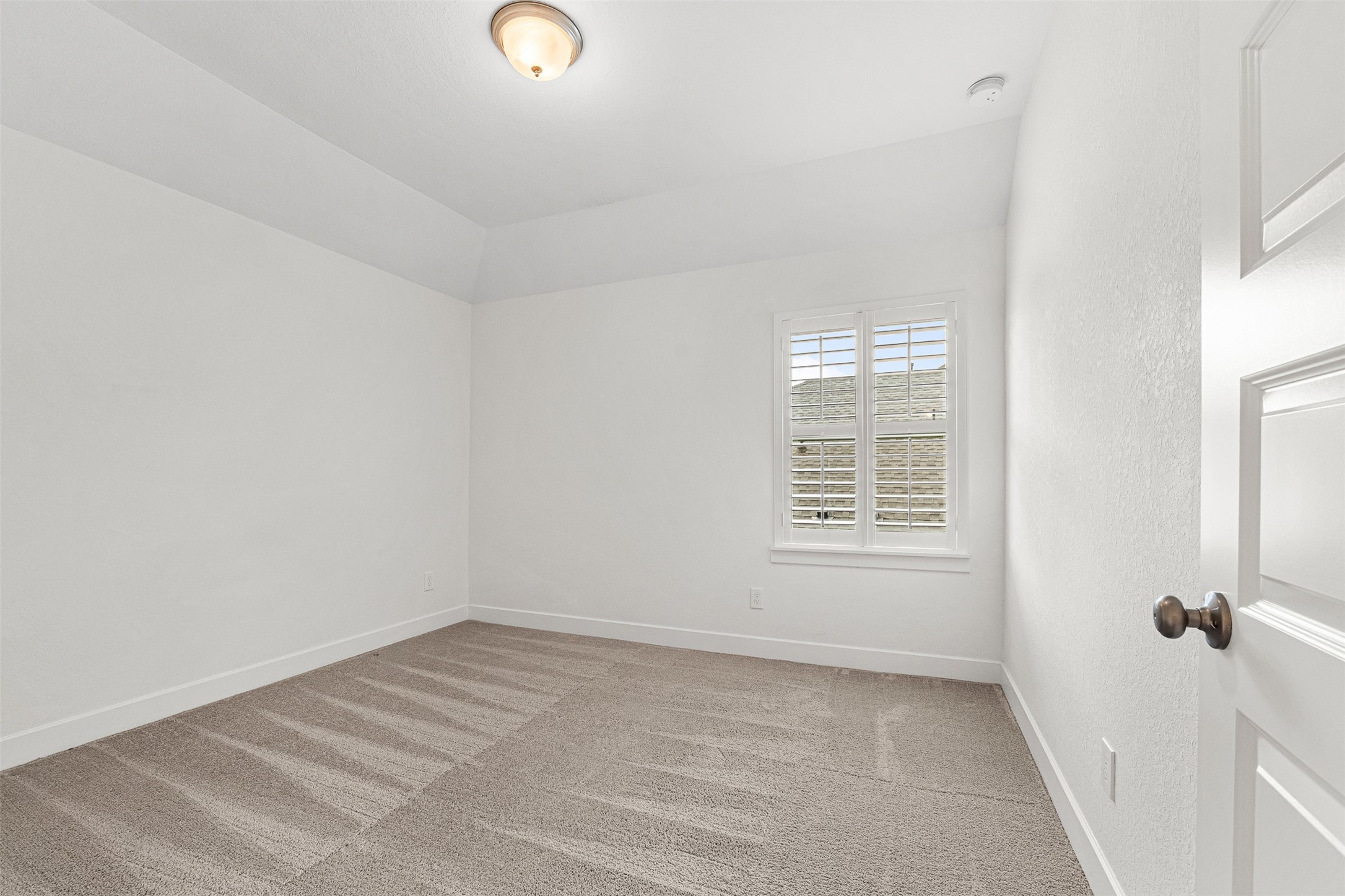 Soft carpet flooring and crisp white plantation shutters highlight this secondary bedroom, complete with a stepped ceiling and versatile layout.