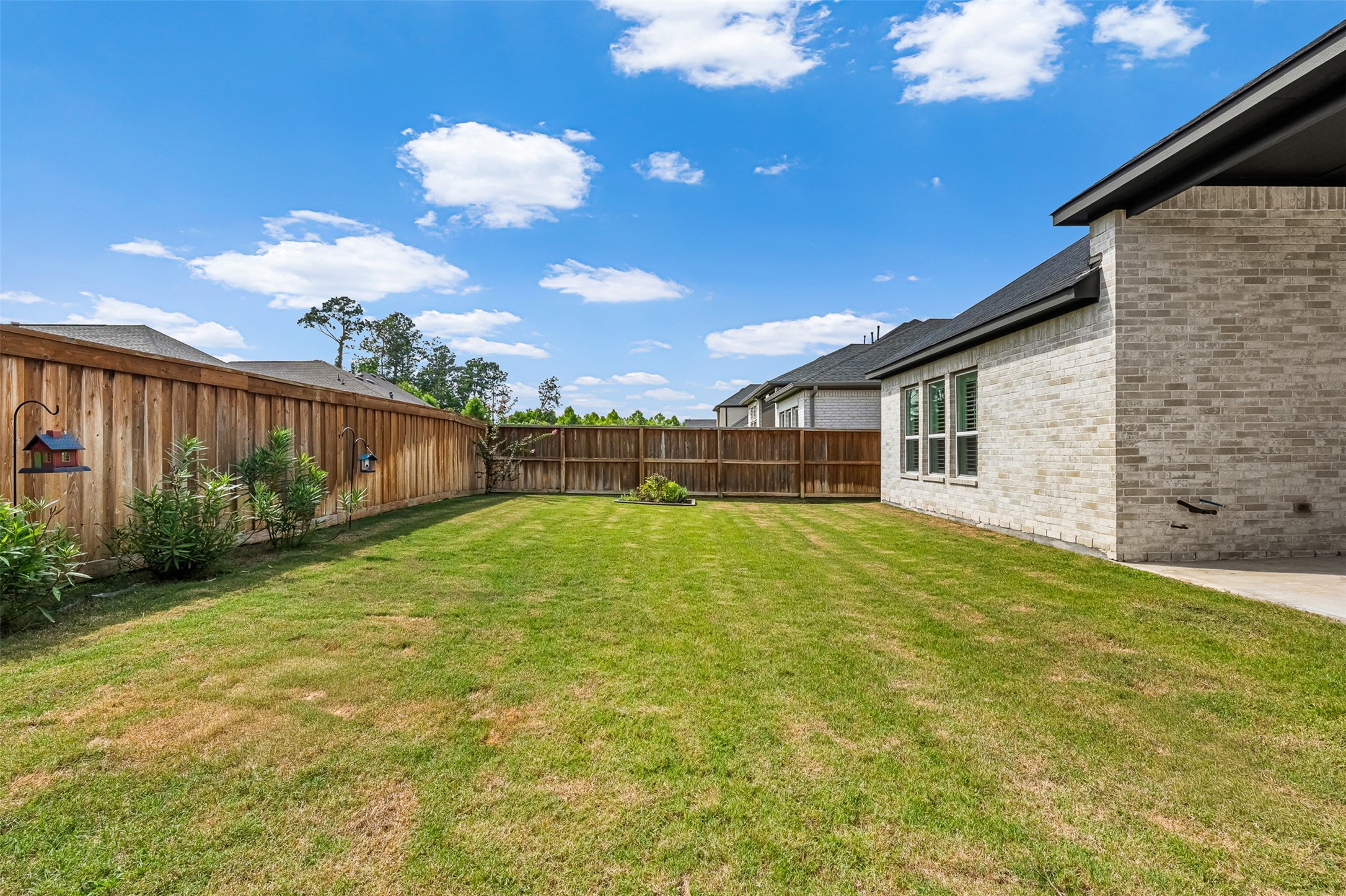 Expansive green space and a high privacy fence define this level backyard, offering endless possibilities for outdoor enjoyment.