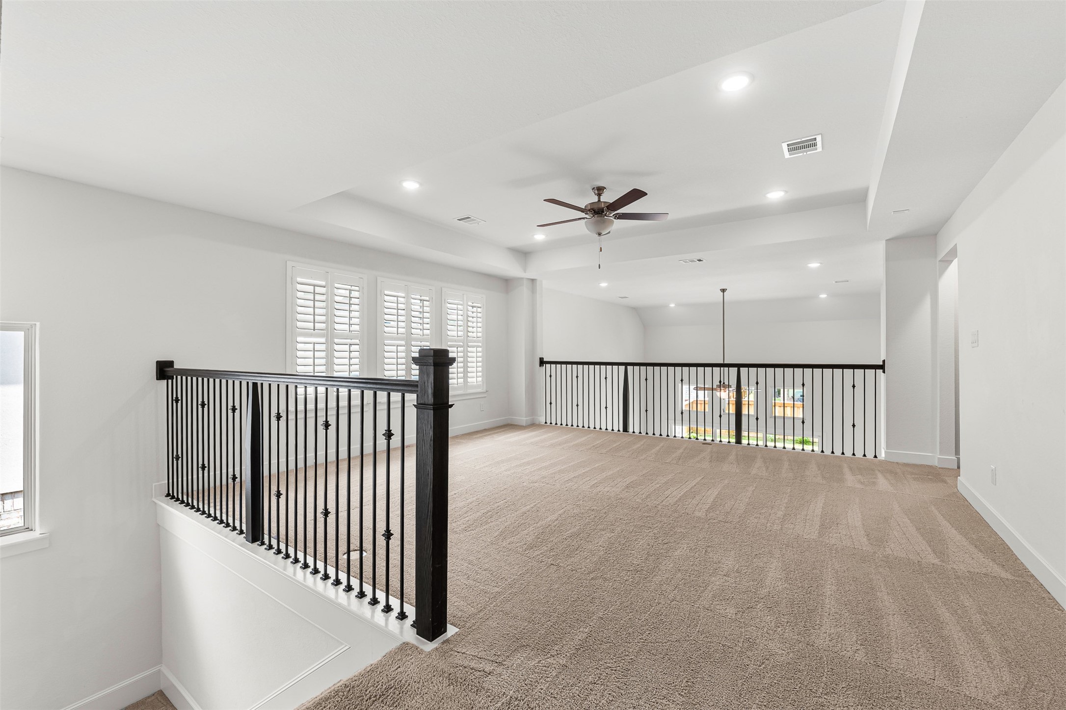 Perched above the main living area, this versatile second-floor flex space features plush carpeting, wrought-iron railings, and classic plantation shutters. The airy open loft overlooks the lower level, creating an ideal spot for an upstairs game room or casual lounge.