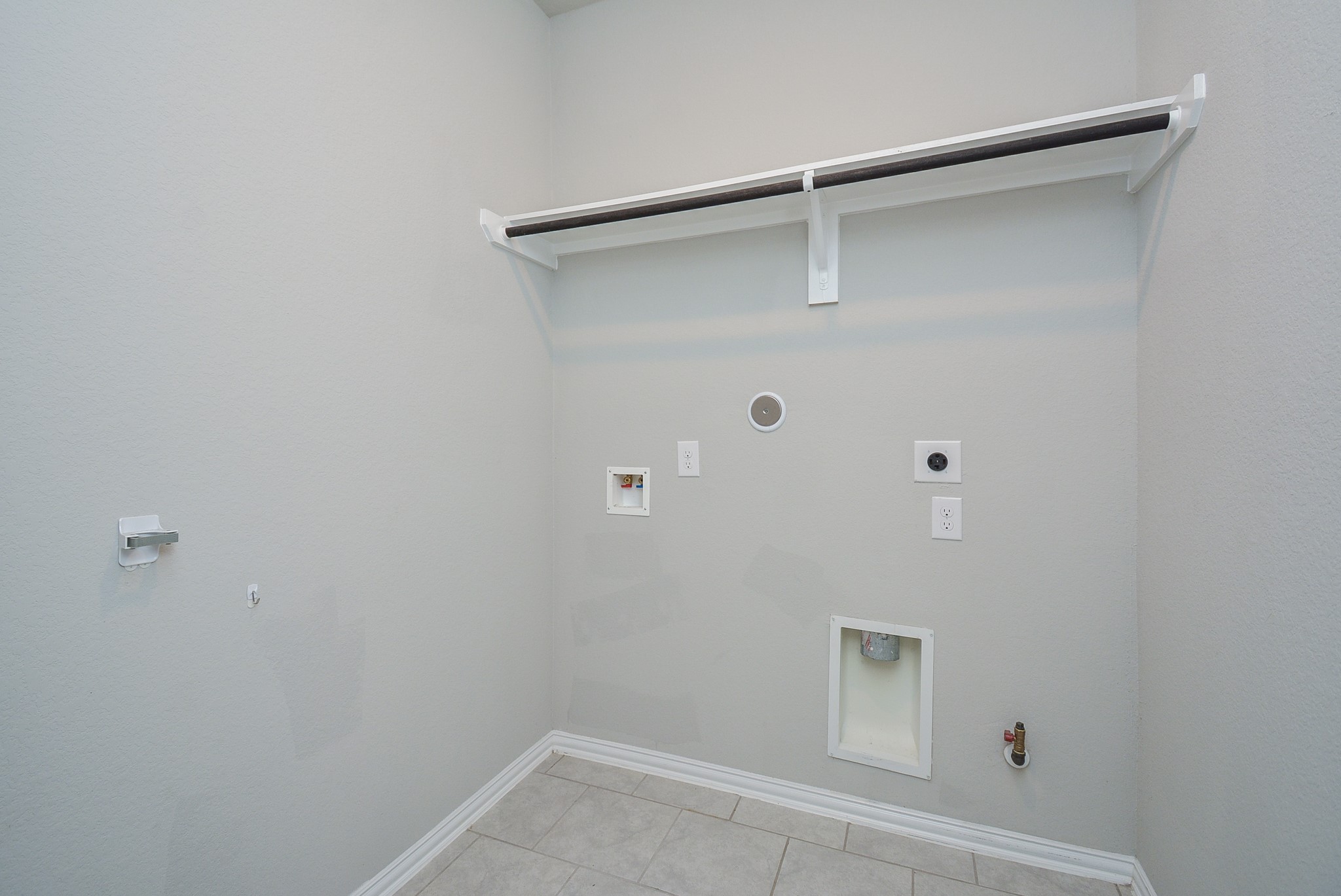 The utility space is ready for dual laundry appliances, with handy shelving above.