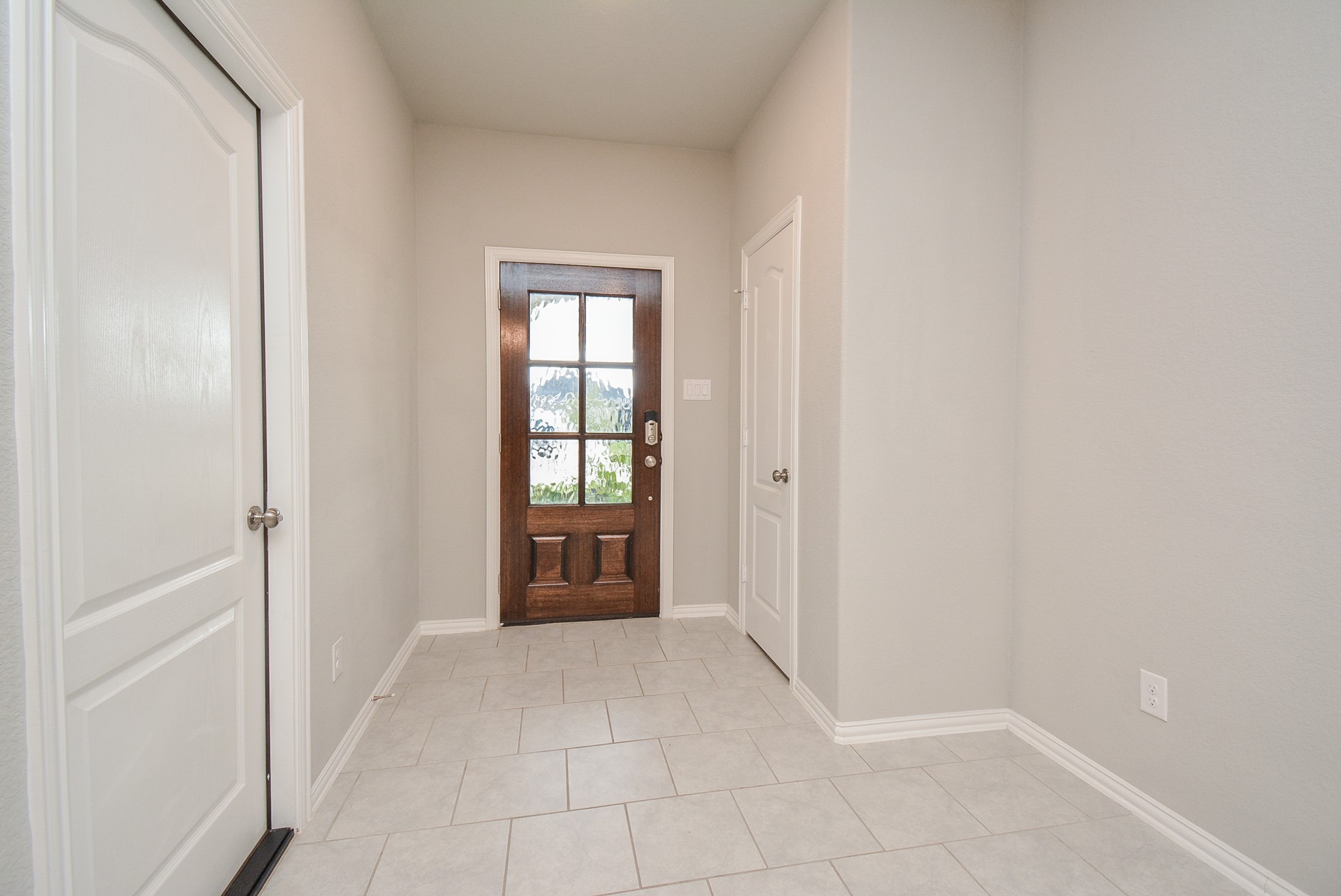 The front entrance/foyer from the inside is bright with pale, neutral walls and beautiful tile flooring, which covers all common areas. (The bedrooms are carpeted.)