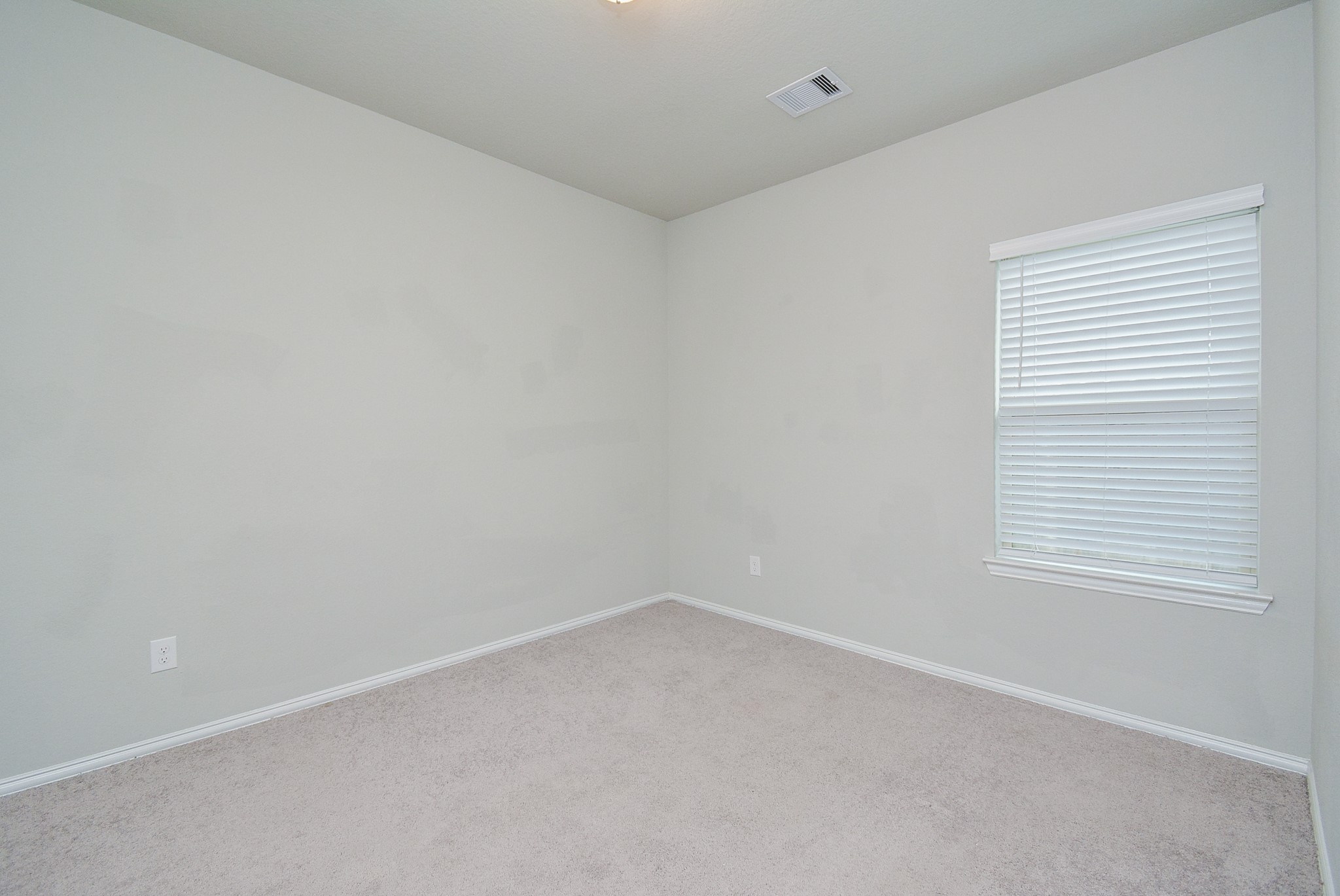 A corner window in a secondary carpeted bedroom means more wall and floor space!