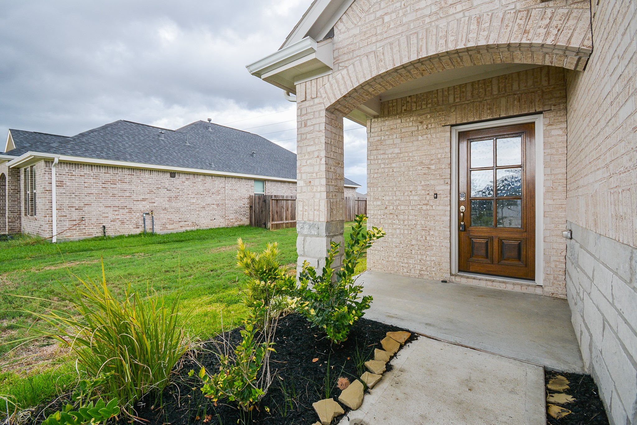 A generous planting bed offers a green welcome as you walk to the covered main entrance, which shares a sizeable front porch.