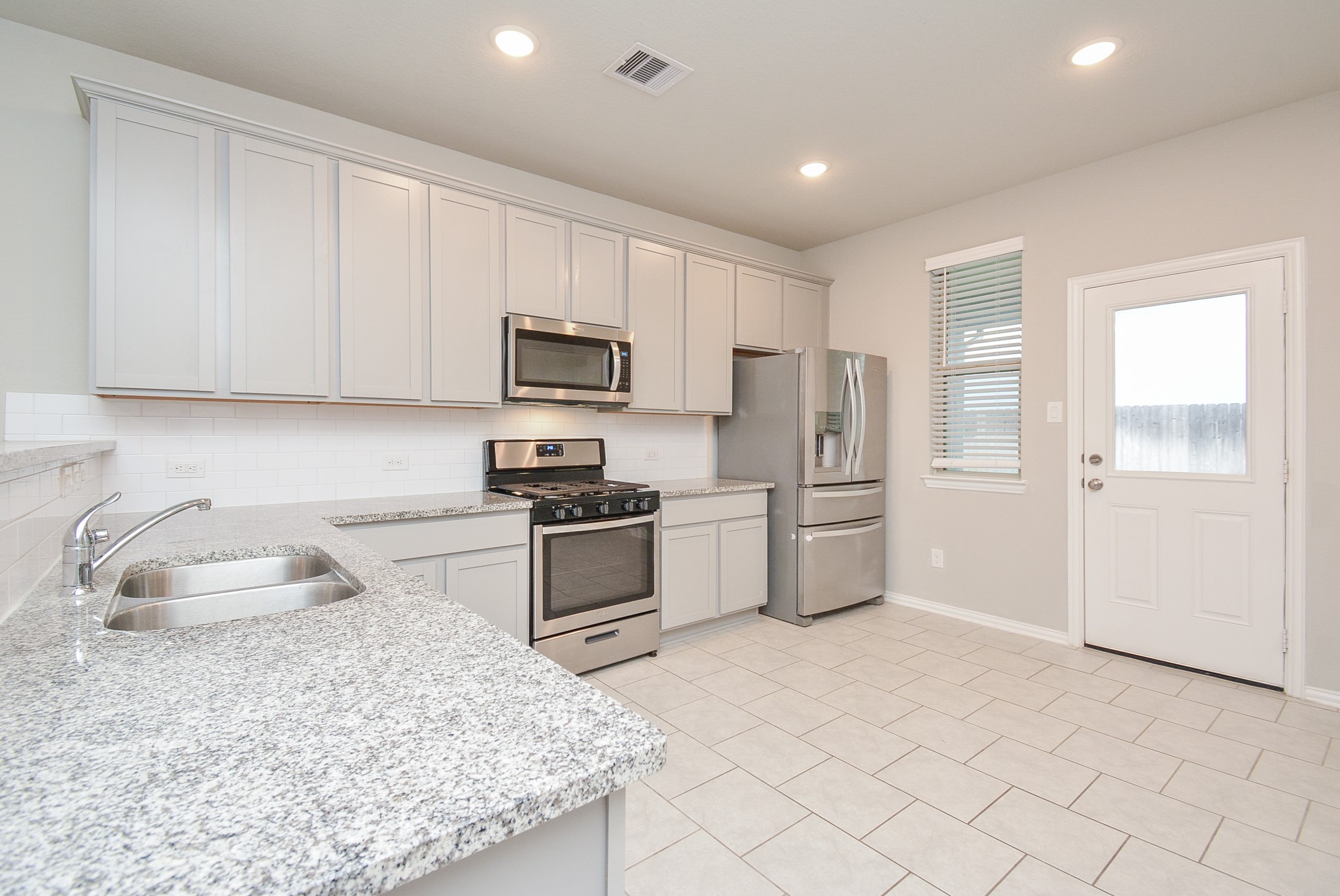 The easily workable kitchen features creamy granite countertops, everywhere, with good storage cabinetry, shining tile backsplash and stainless steel appliances.