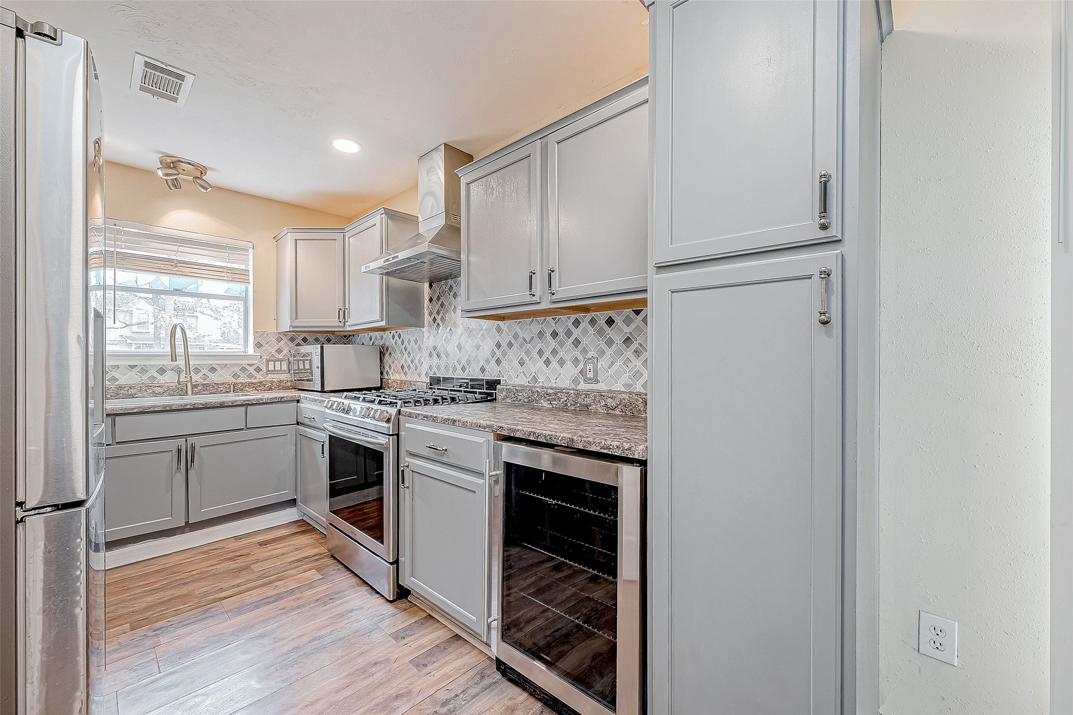 The kitchen combines style and practicality with a sleek gray palette of cabinetry and backsplash that pairs beautifully with polished countertops. Thoughtful lighting ensures every corner is illuminated, while plentiful storage makes organization straightforward.