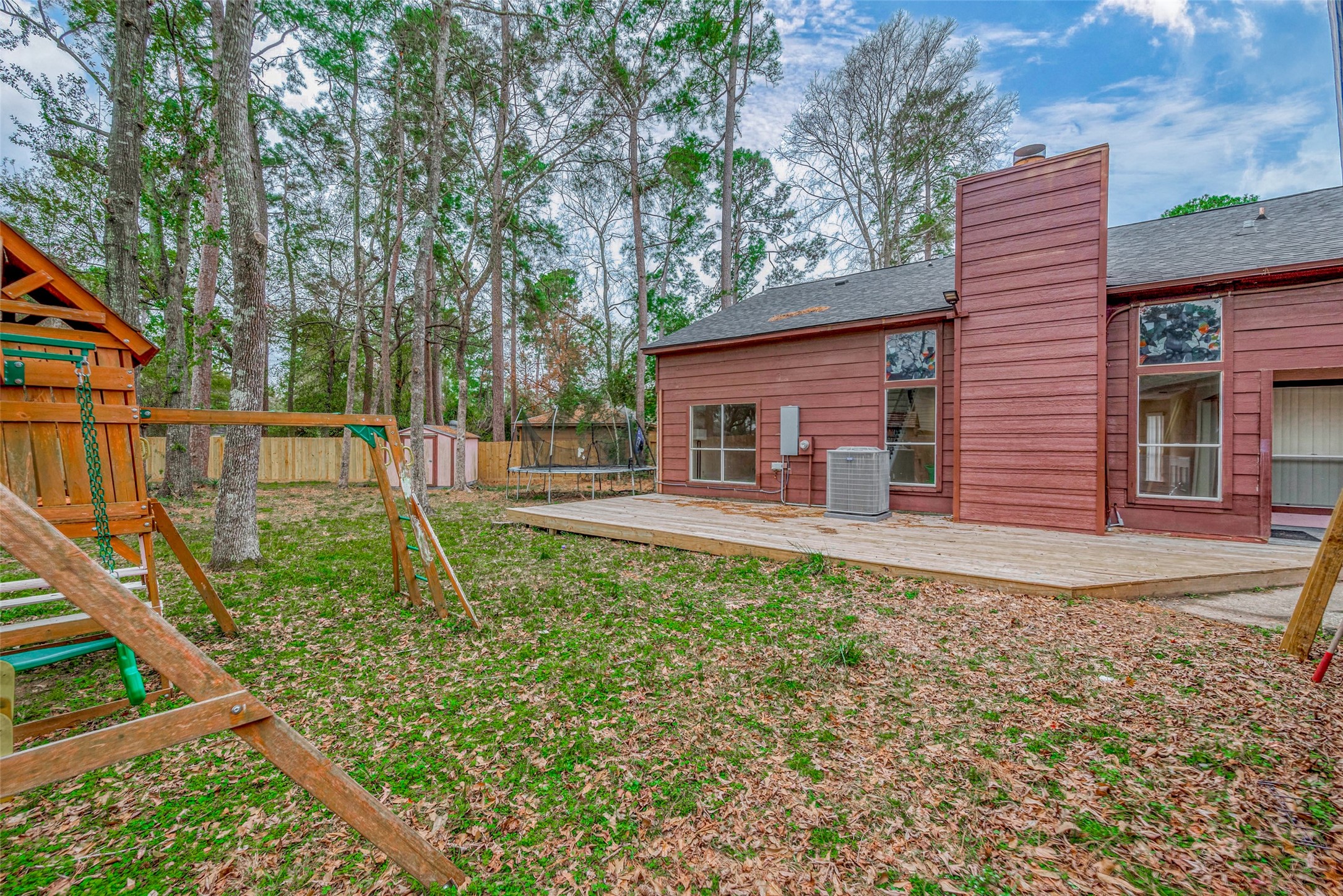 The fully fenced backyard offers an expansive grassy area, perfect for outdoor activities or relaxation. A spacious wooden deck provides ample room for seating, while a storage shed adds convenience.