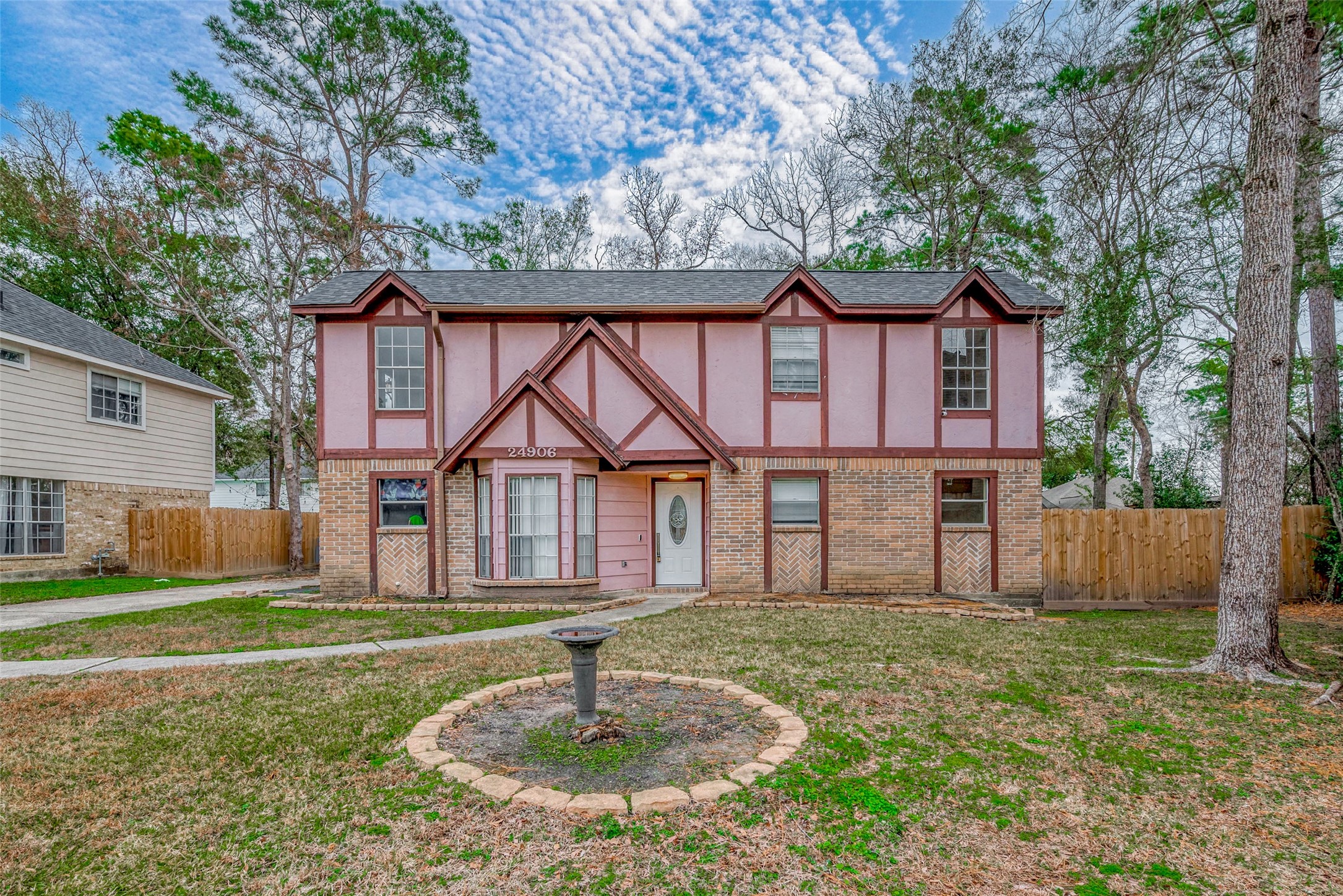Nestled in a peaceful cul-de-sac, this home boasts a striking exterior that pairs classic brickwork with natural wood elements. The expansive front yard is framed by a long driveway and a walkway that gracefully cuts through the lush, green lawn, guiding you toward the front entrance.
