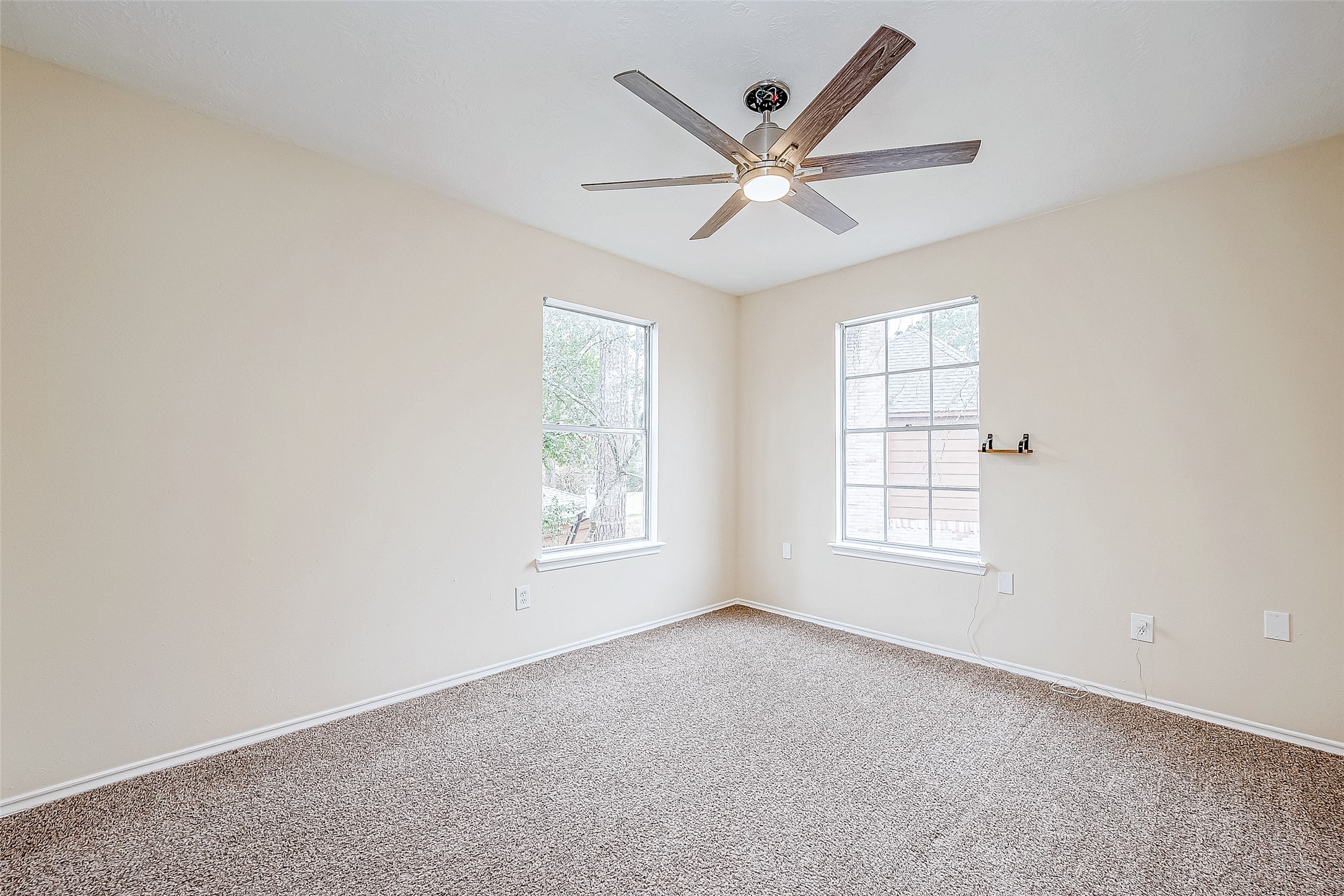 This bedroom is both spacious and inviting, featuring soft carpeting, large windows that frame outdoor views, and a ceiling fan for added comfort. A well-sized closet provides ample storage.