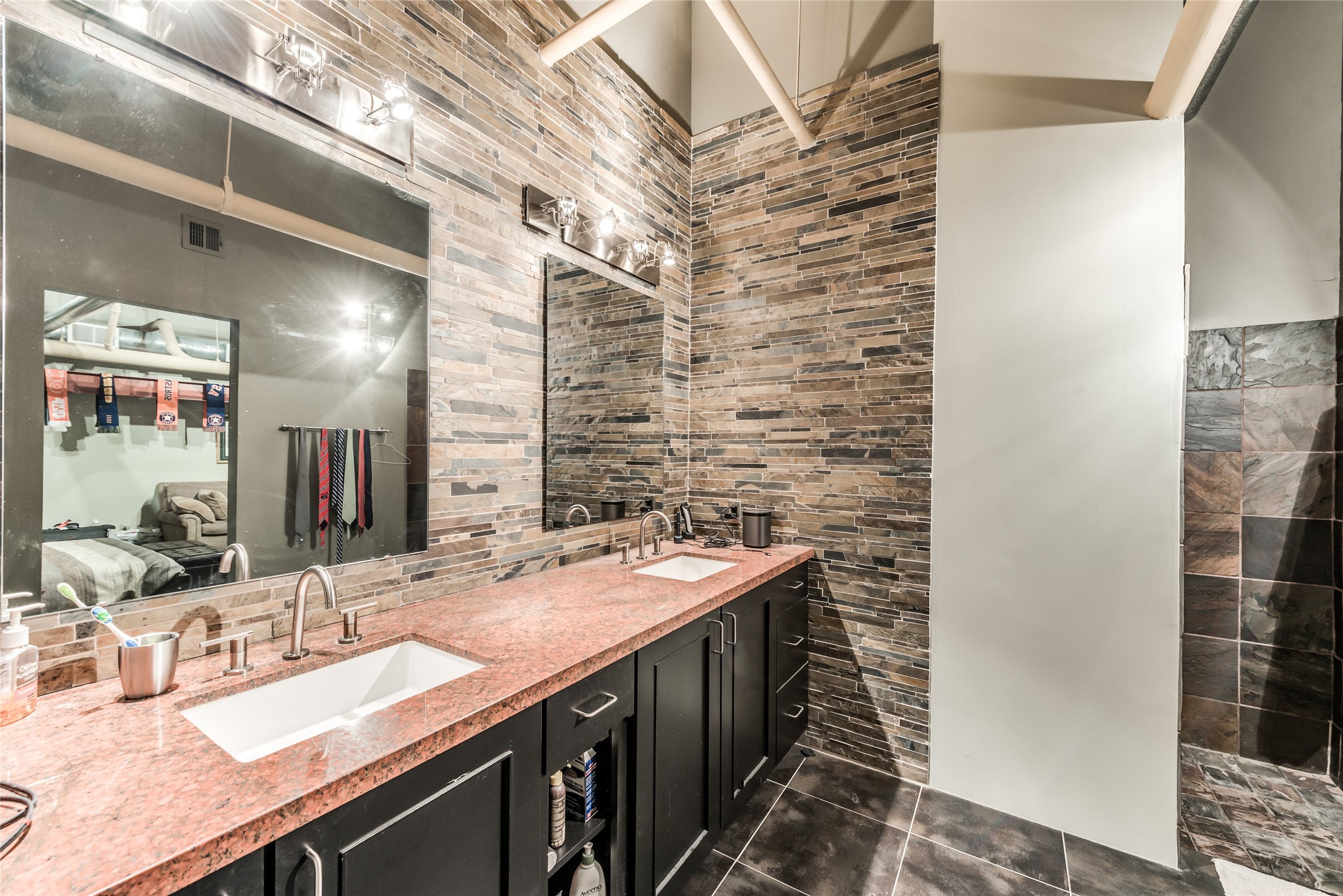 This modern bathroom features a dual-sink vanity with sleek granite countertops and dark cabinetry.