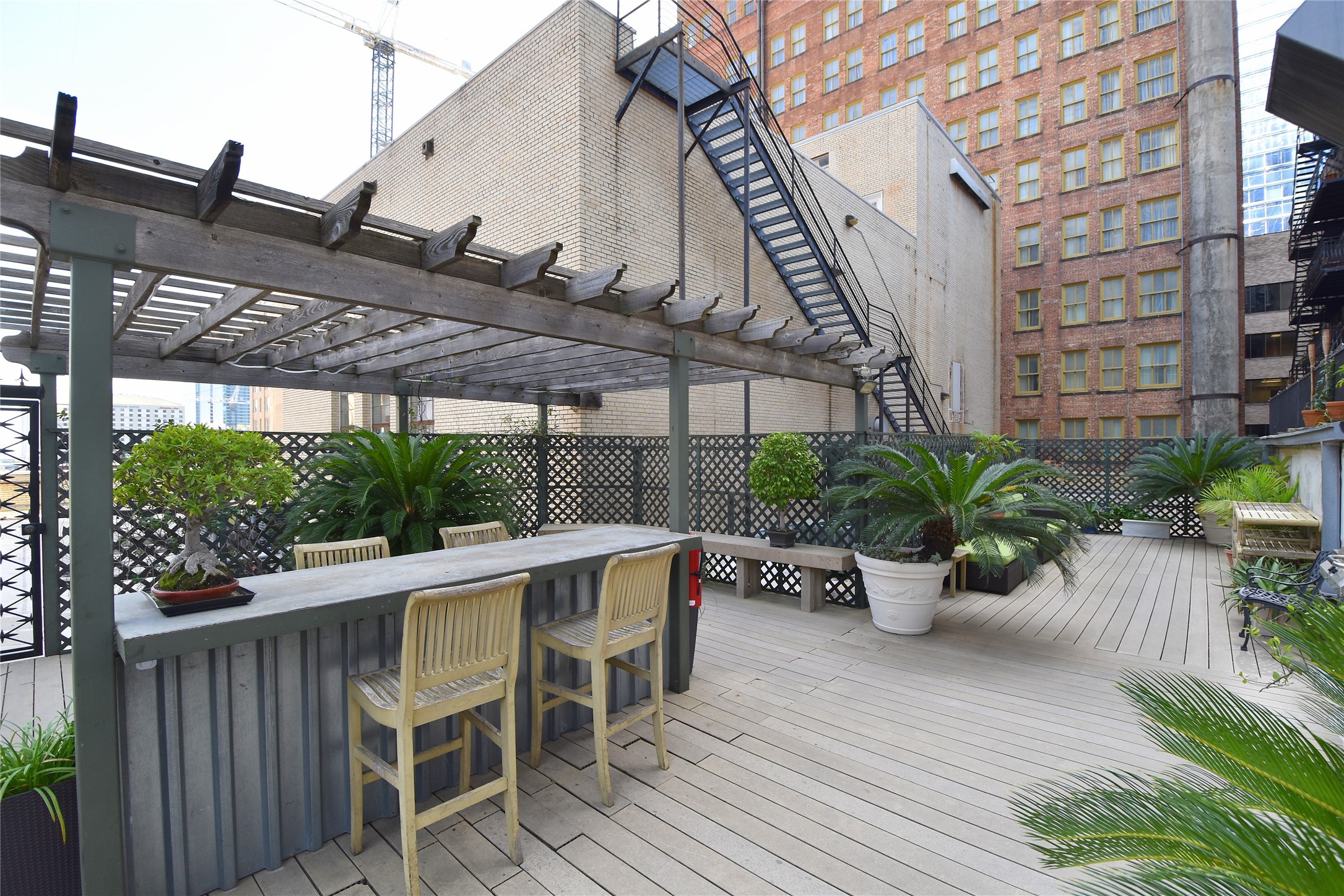 Spacious urban rooftop deck with a pergola, bar seating.