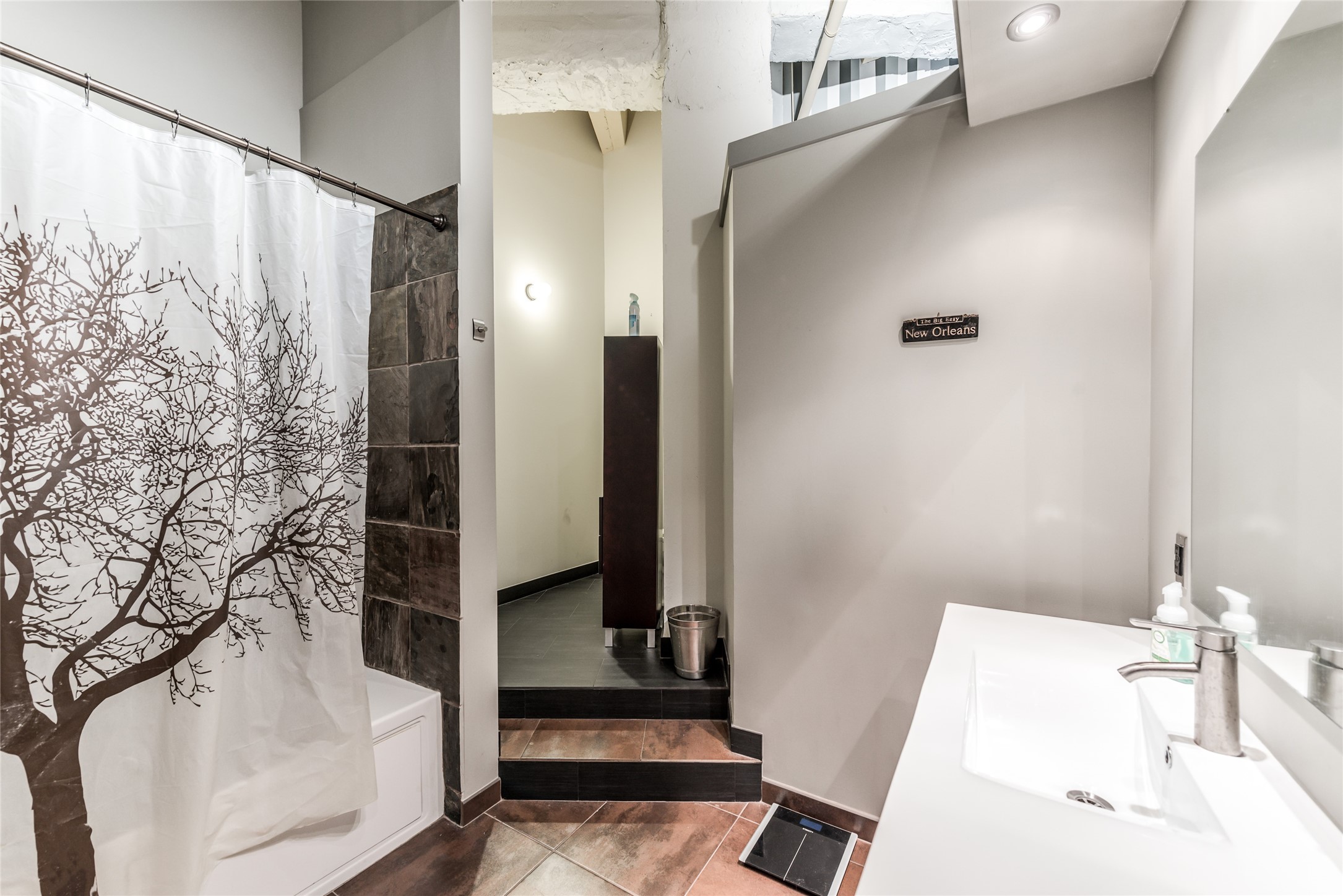 Secondary Bathroom features a modern design with slate tile accents, and a sleek white vanity.