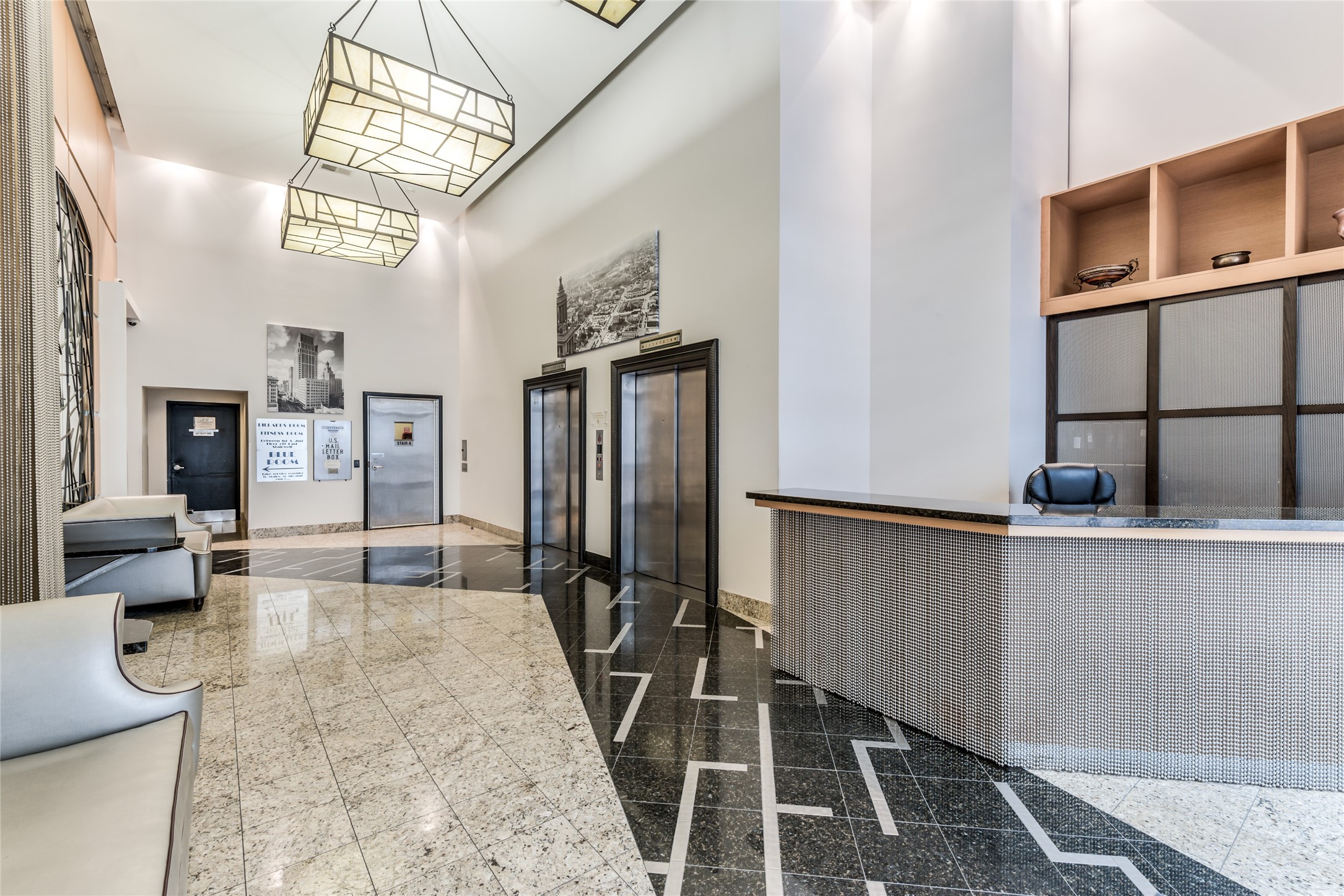 Well-lit lobby featuring sleek granite flooring, contemporary lighting fixtures, and a stylish concierge desk.