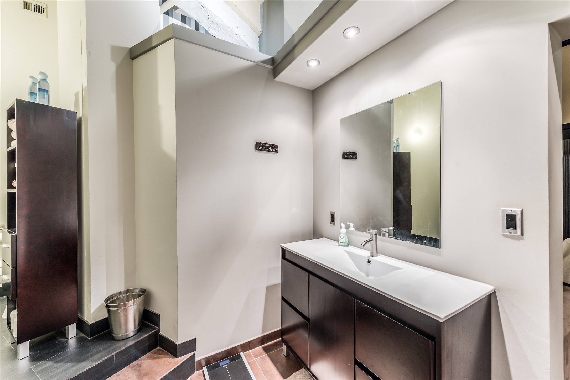 Secondary Bathroom features a modern vanity with a large mirror, recessed lighting, and sleek cabinetry.