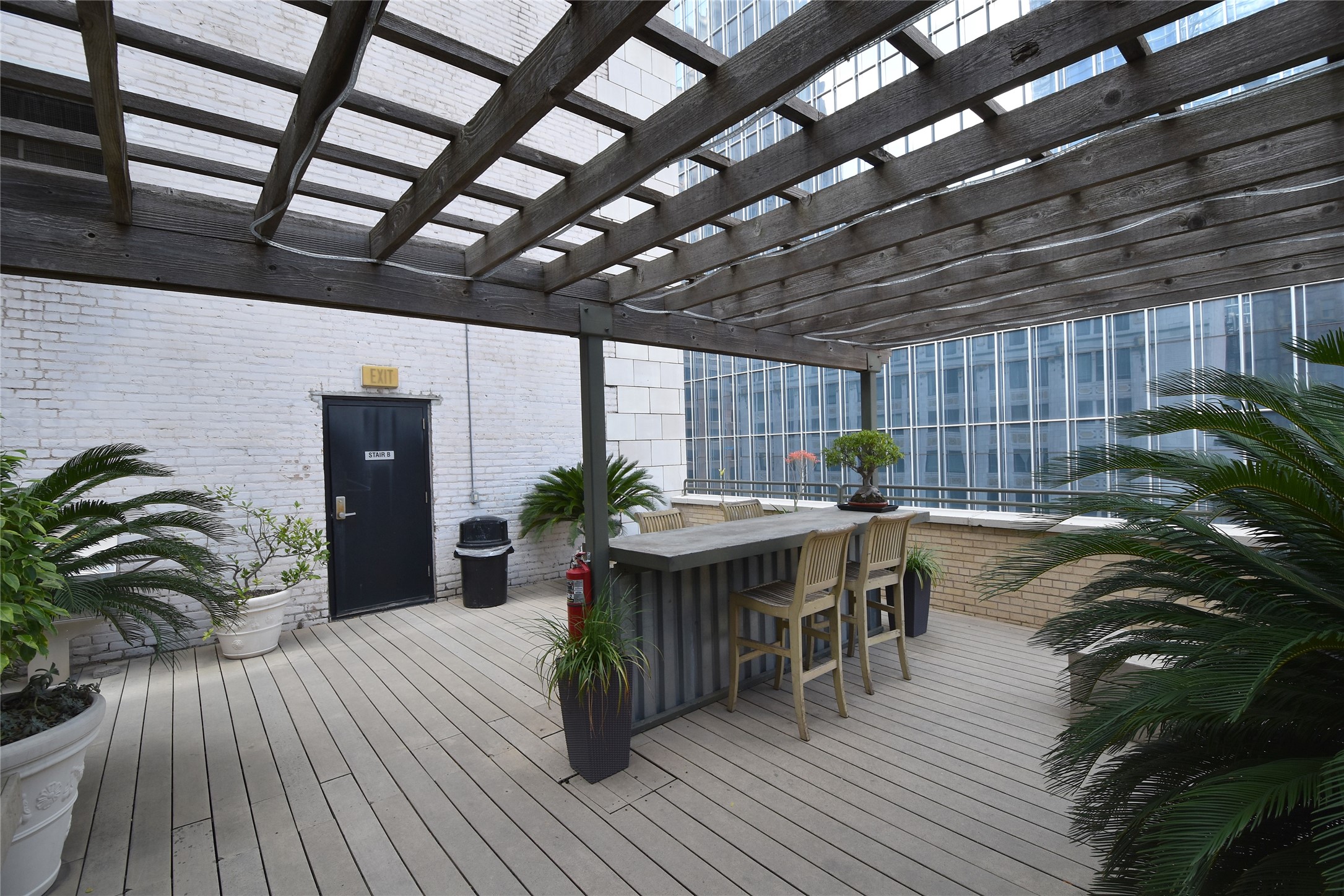 Stylish rooftop patio with a wooden pergola, bar seating.