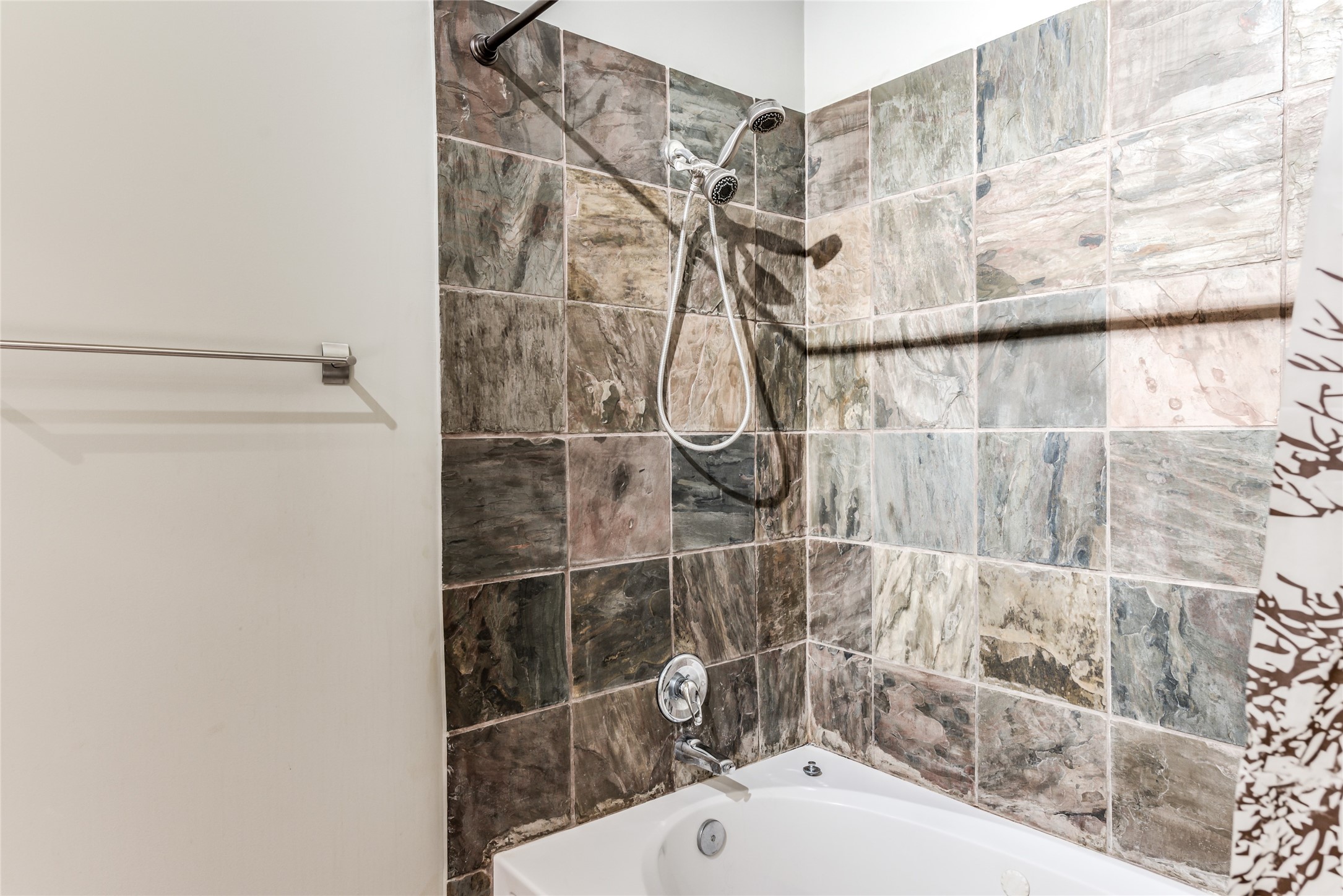This bathroom features a tub-shower combination with a modern tile surround, offering a clean and stylish look.