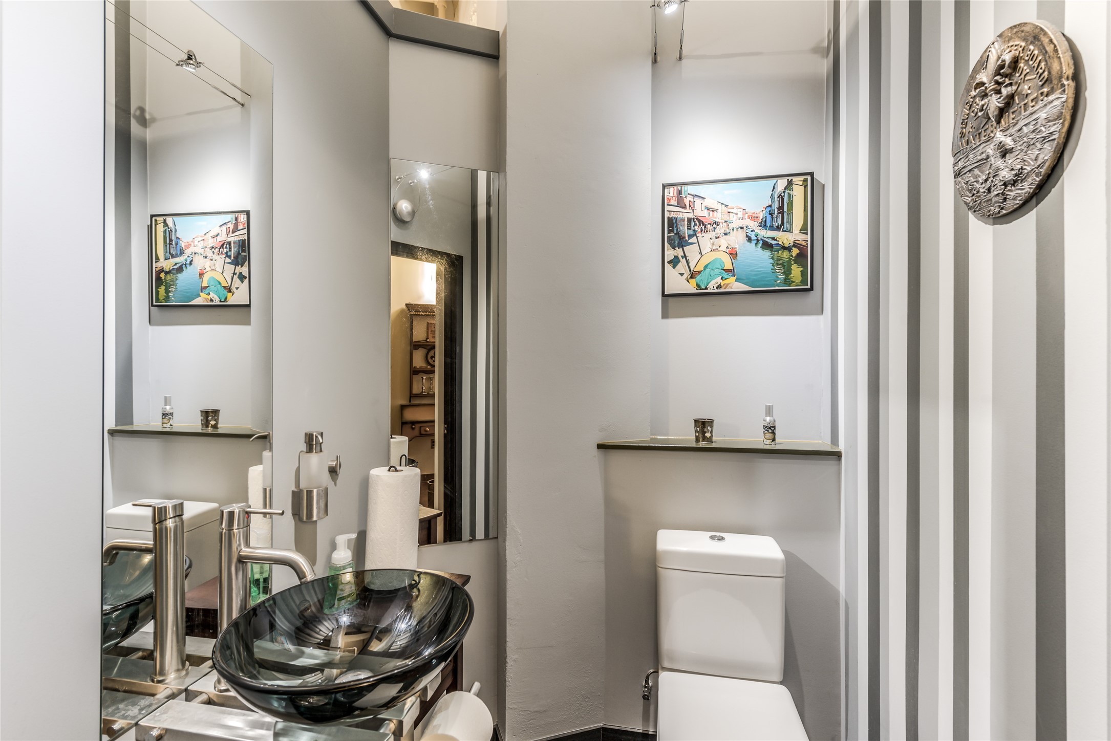 Half Bath features a sleek glass vessel sink, elegant fixtures, and stylish striped walls.