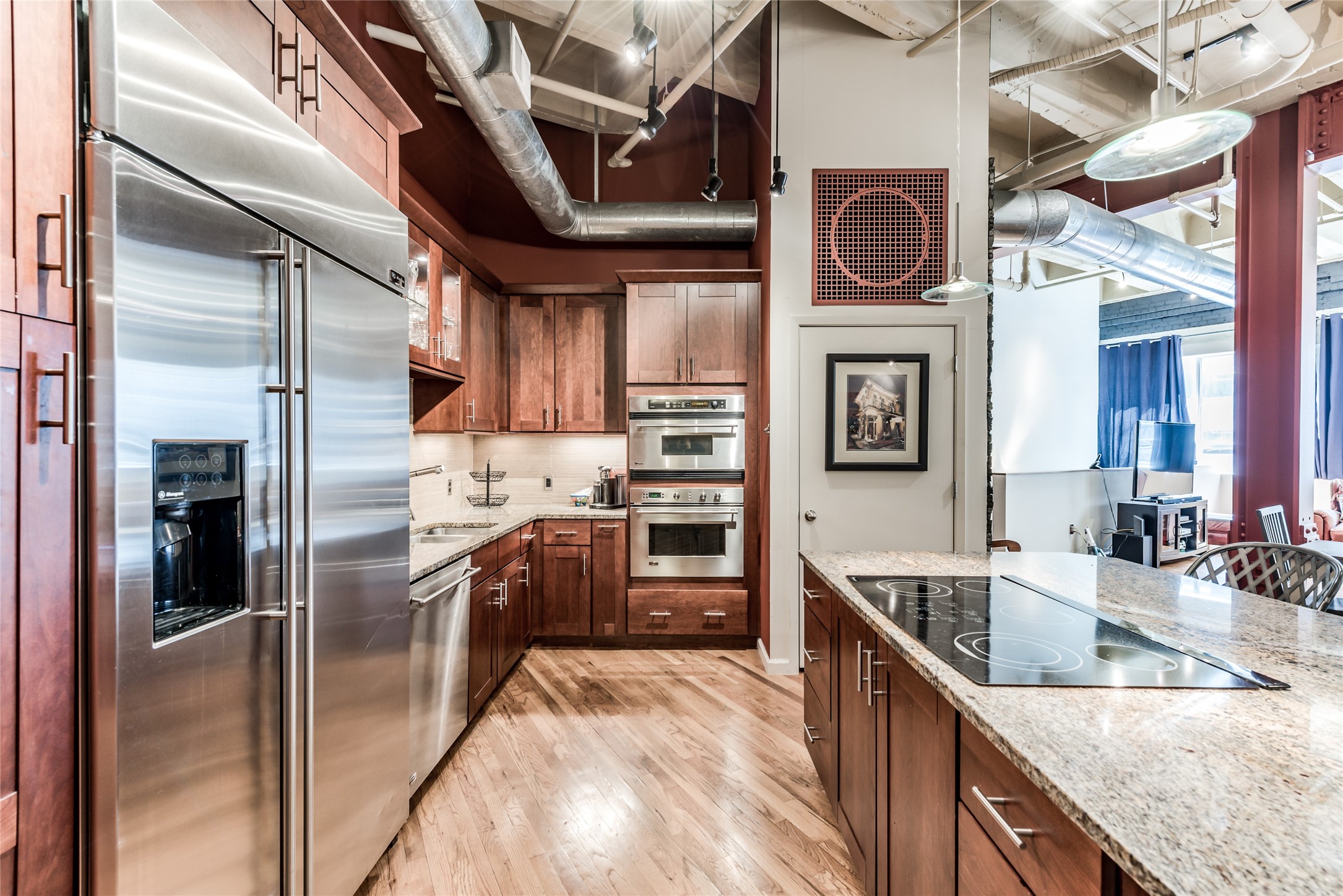 This modern kitchen features stainless steel appliances, wood cabinetry, and a spacious granite island with an electric cooktop.