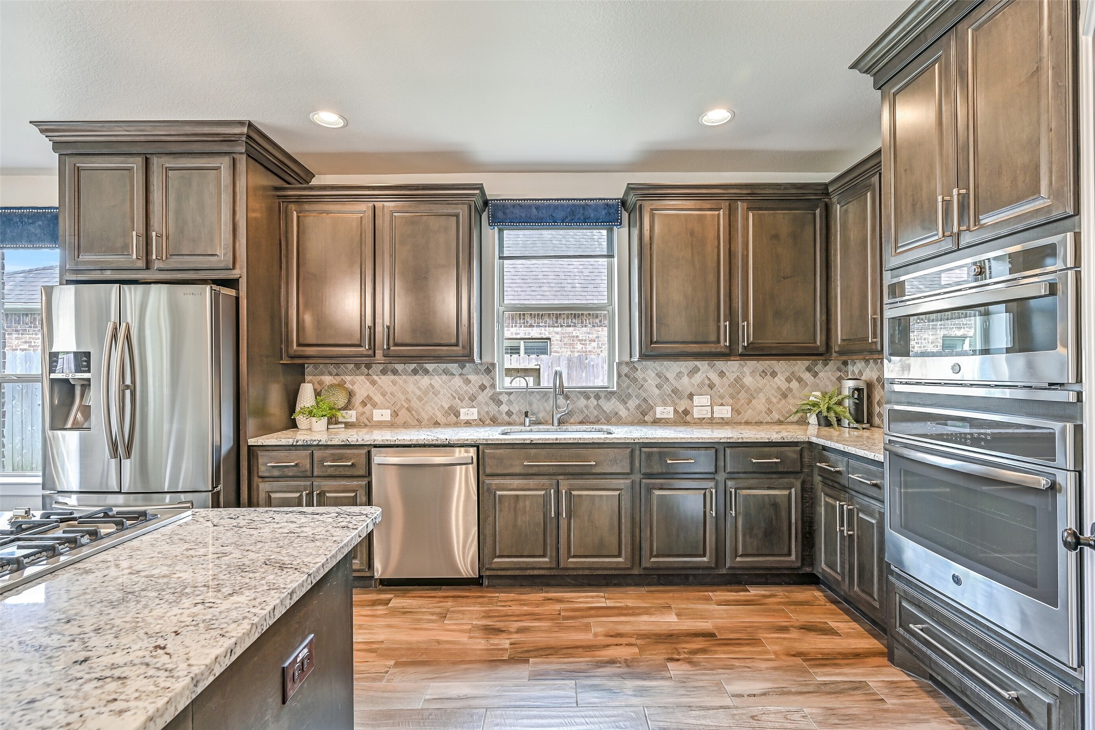 Another view highlights the kitchen's abundant cabinetry, granite work surfaces and stainless appliance package, including the GE electric convection oven and built-in microwave. The dishwasher and microwave were updated in 2025.