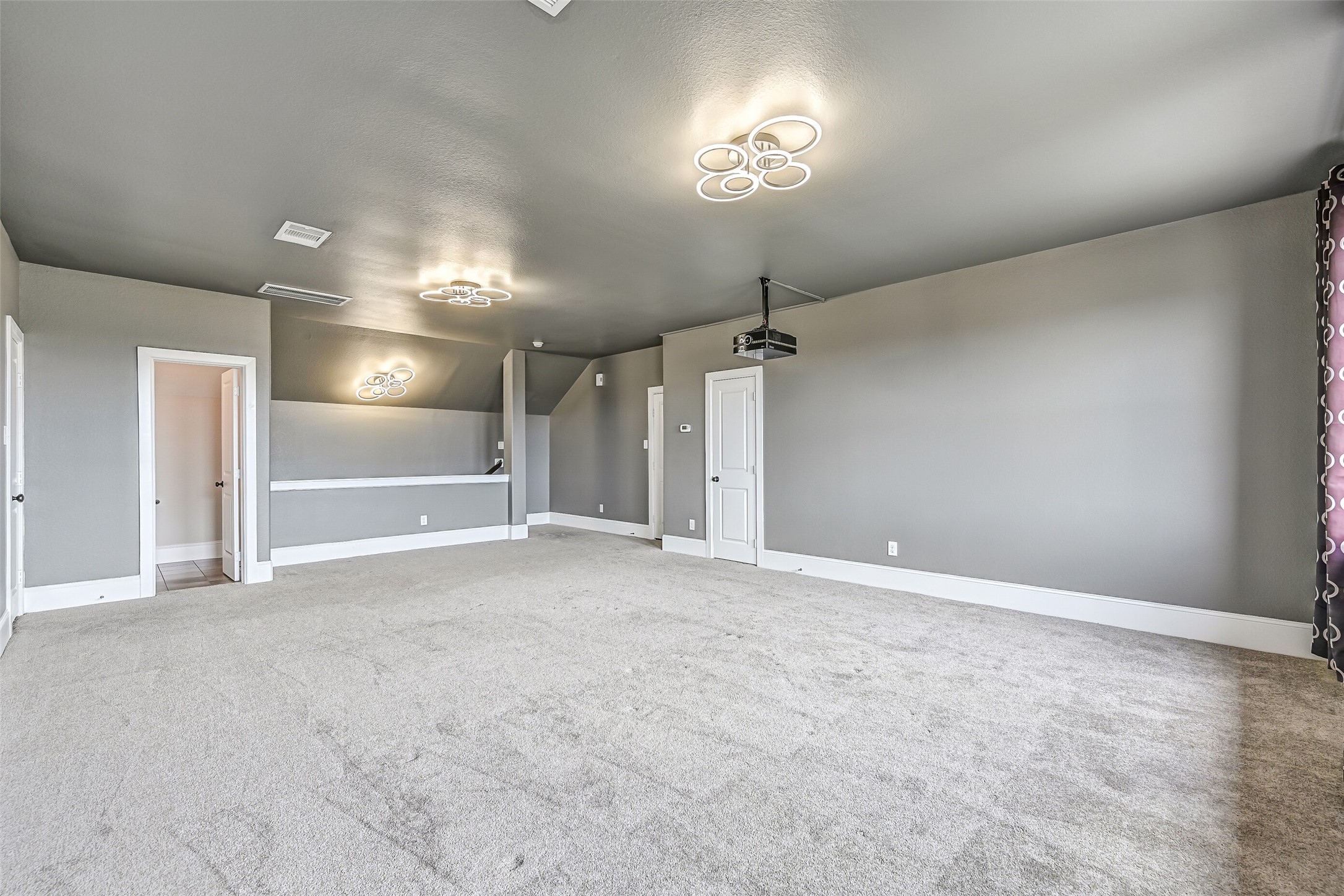 A huge 26' x 18' third-floor media room provides an impressive additional living space with plush carpet, modern lighting, mounted projector and convenient walk-in attic access on both sides.