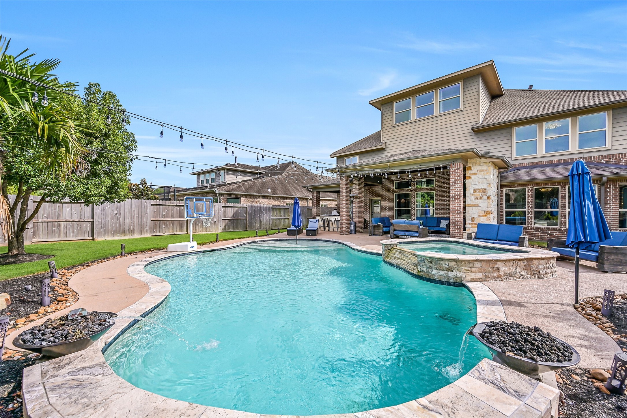 The backyard centerpiece is a heated PebbleTec pool with travertine coping and oversized raised spa, surrounded by generous decking, mature landscaping and the expansive covered outdoor living area.