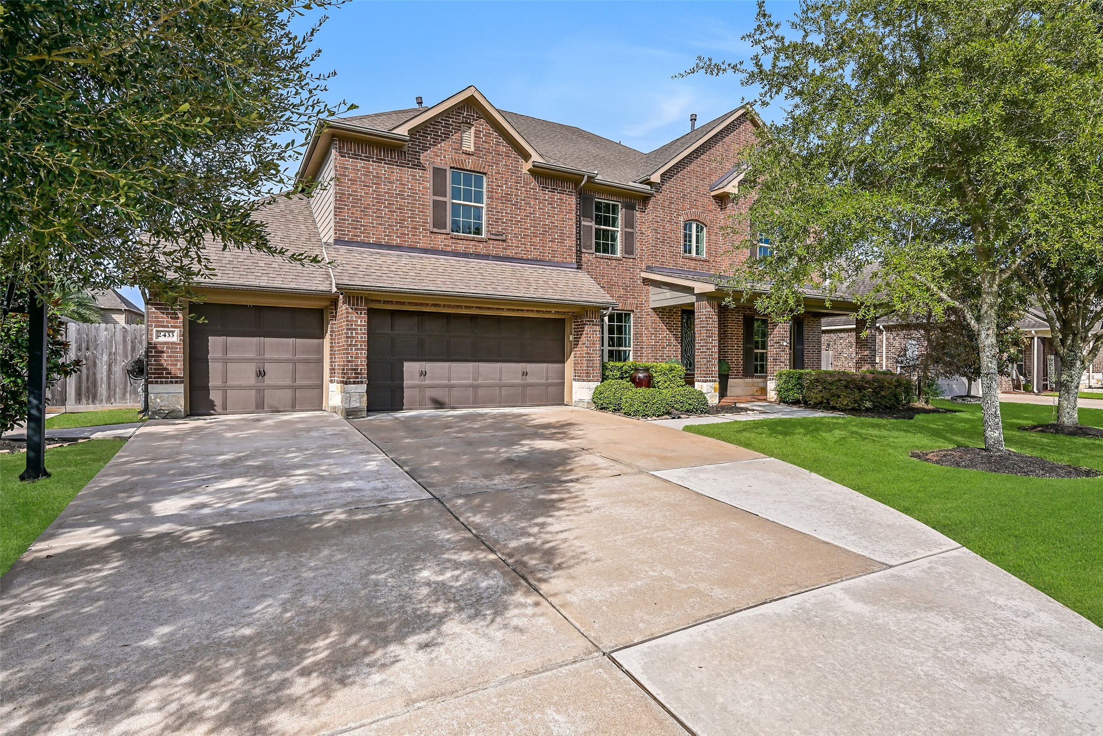 This angle of 2433 Prairie Mist highlights the spacious 3-car garage, wide driveway & attractive brick elevation, framed by mature landscaping and established trees. The insulated and finished garage offers extensive workshop cabinetry and storage inside.
