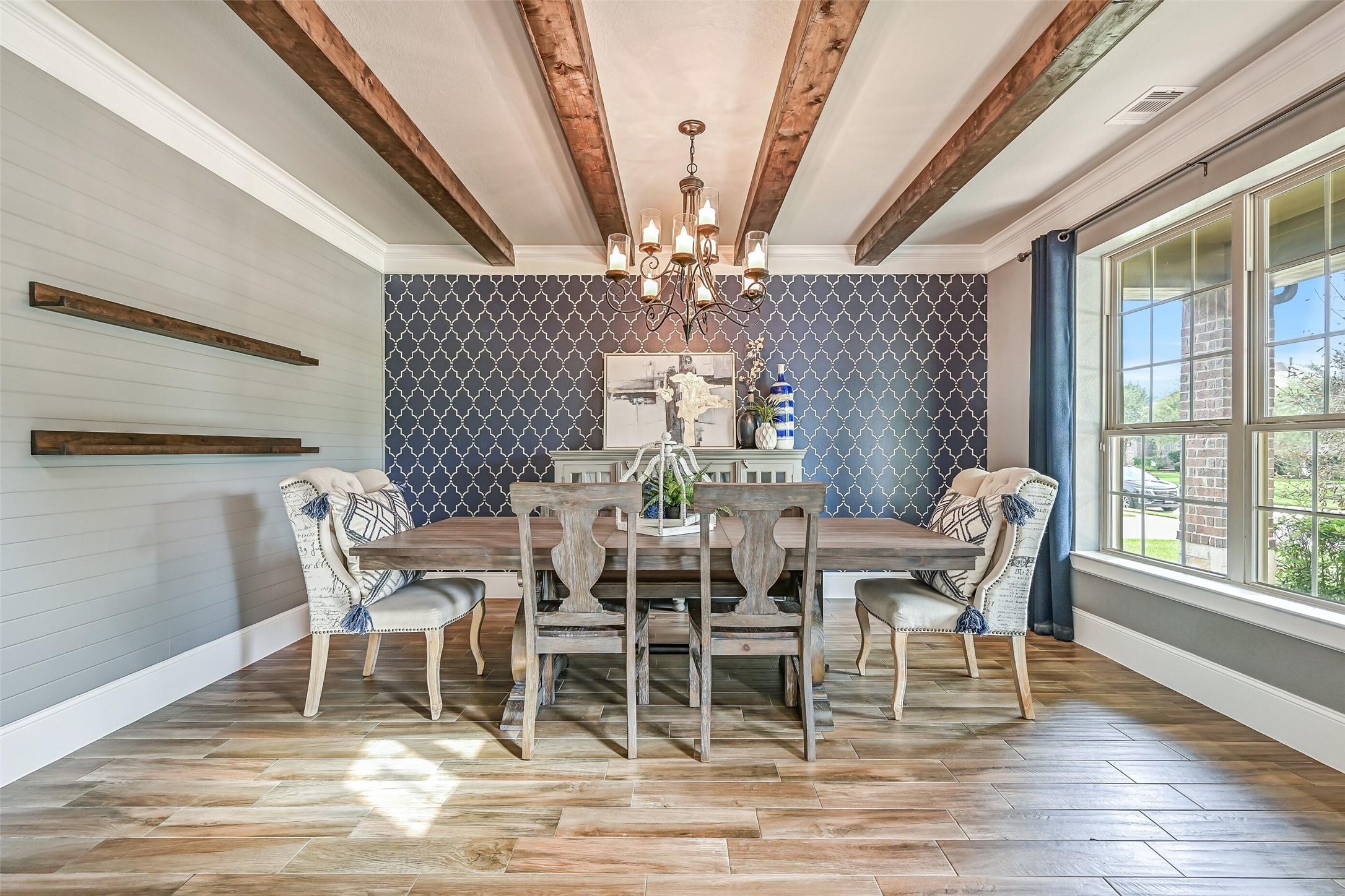 Another view showcases the dining room's dramatic custom painted navy geometric accent wall and contrasting grey shiplap treatment, while a large front-facing window fills the space with natural light.