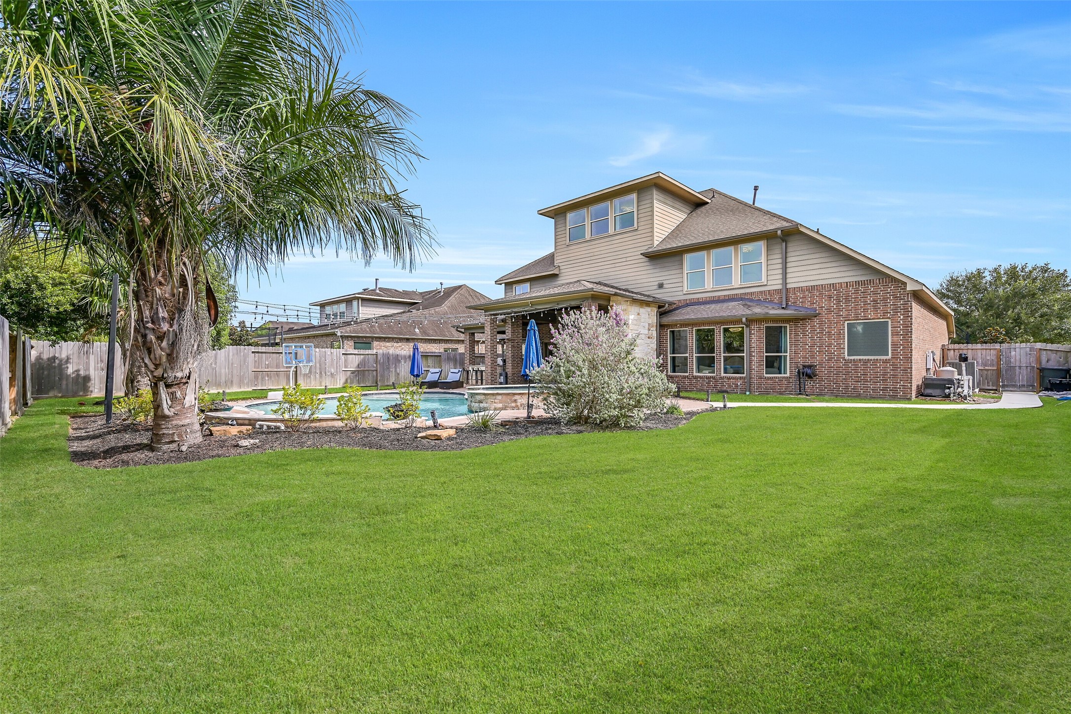 A generous lawn remains beyond the pool and outdoor living areas, framed by mature palms and manicured landscaping. The 2024 fence, irrigation & landscape lighting are joined by a paved walkway providing convenient access to the pool equipment and side gate.