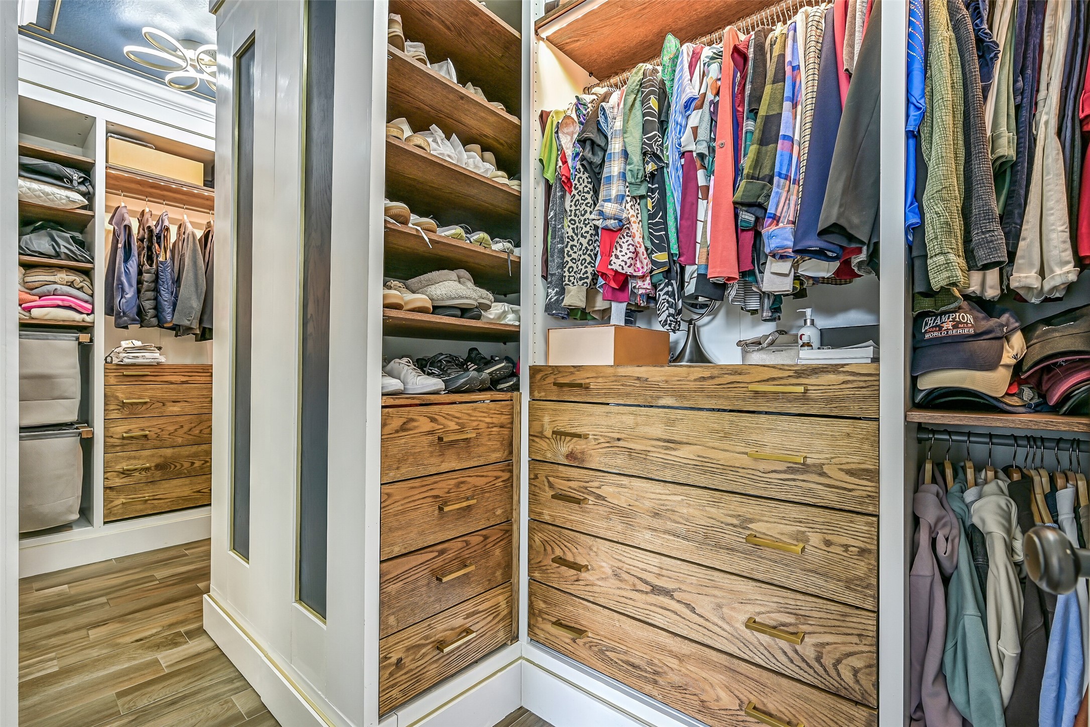 The fully customized primary closet offers exceptional organization with extensive hanging space, wood shelving and drawers, integrated lighting, mirrors and dedicated accessory storage.