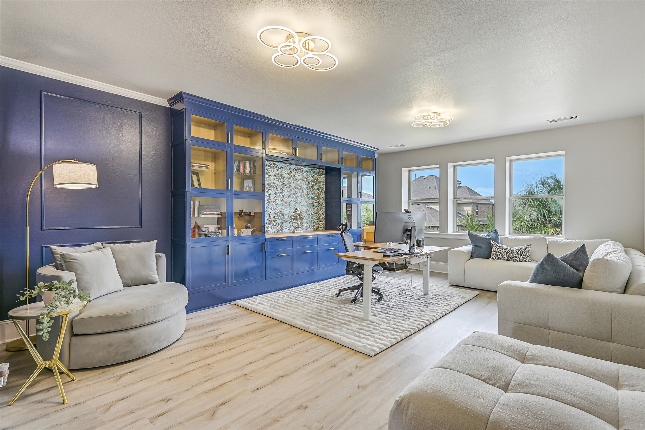 The spacious second-floor gameroom offers LVP flooring, modern lighting, a wall of rear-facing windows with pool views and an impressive custom built-in with glass-front cabinetry, display shelving and abundant storage.