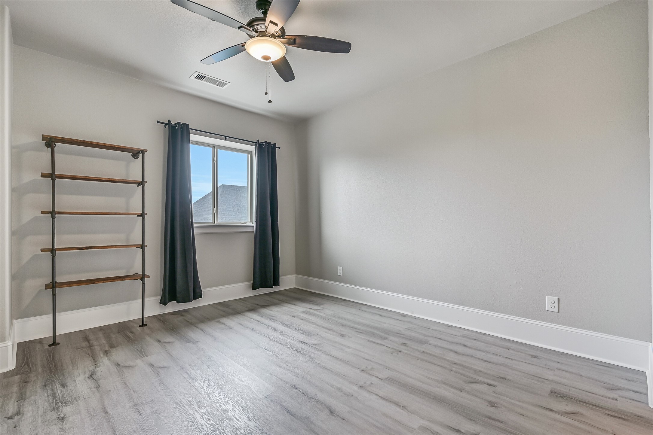 Another generously sized upstairs bedroom offers neutral paint, LVP flooring, a lighted ceiling fan and industrial-style wall shelving, with convenient access to the adjoining Jack & Jill-style bath.