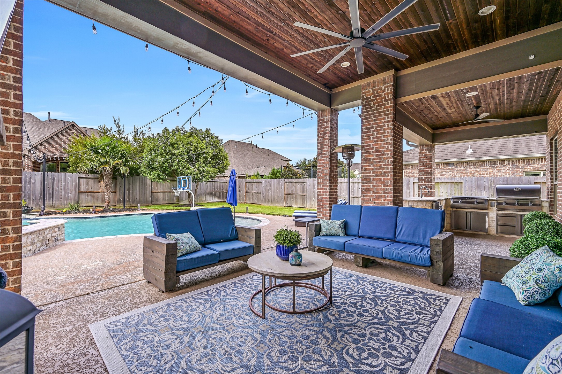 The expansive 32' covered patio creates a true outdoor living space with stained wood ceiling, oversized fans, multiple seating areas and views of the pool. The patio furniture and outdoor TV are included with the home.