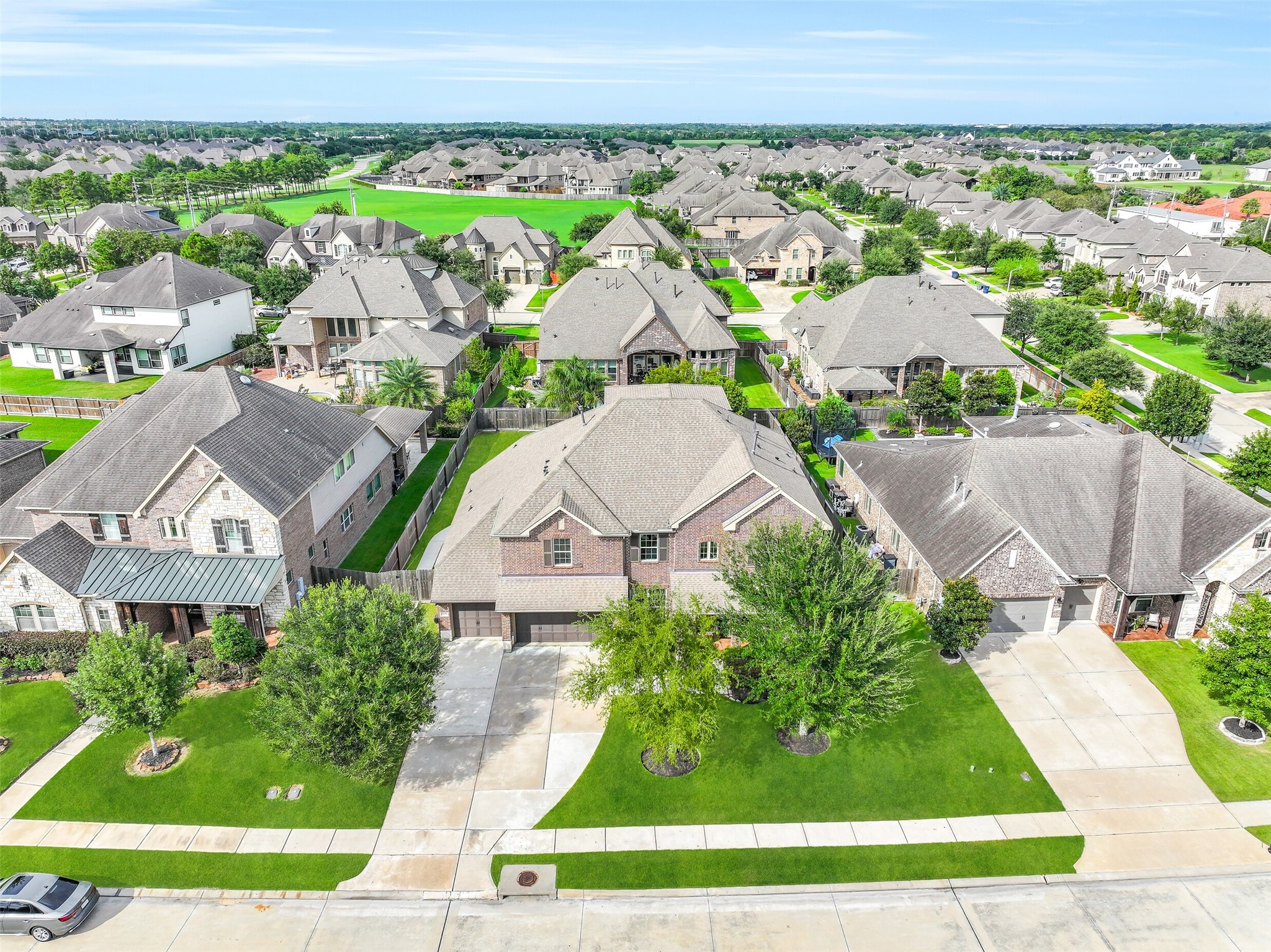 An elevated front view highlights the homes substantial footprint, 3-car garage and manicured setting within gated West Ranch, with the surrounding neighborhood and green space providing a sense of location and scale.