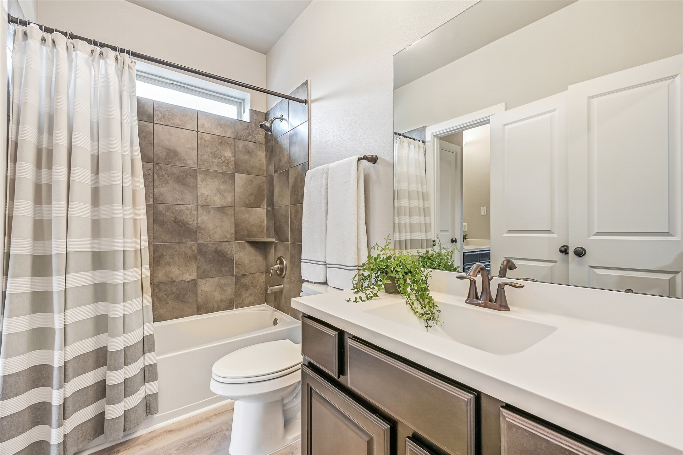 Connecting two secondary bedrooms, this Jack & Jill bath offers dual private vanity areas with cultured-marble counters, rectangular basin sinks, and a tub/shower combination with tiled surround.